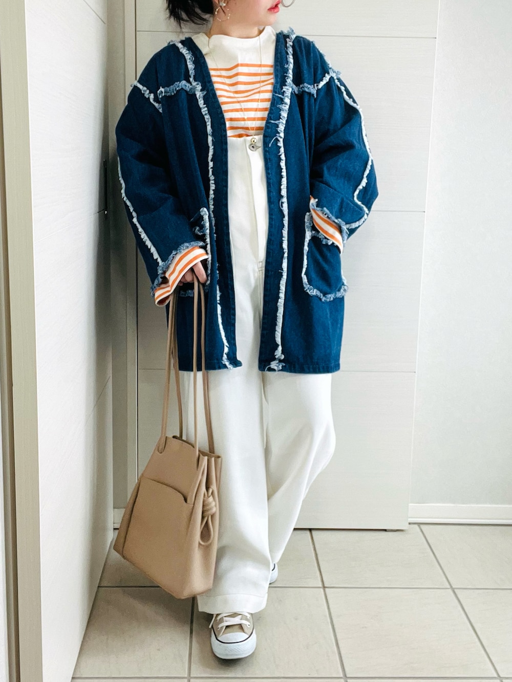 オレンジ系のTシャツ/カットソー、ブルー系のデニムジャケット、ホワイト系のサロペット/オーバーオールを着用したレディースの春コーディネートの2枚目の写真