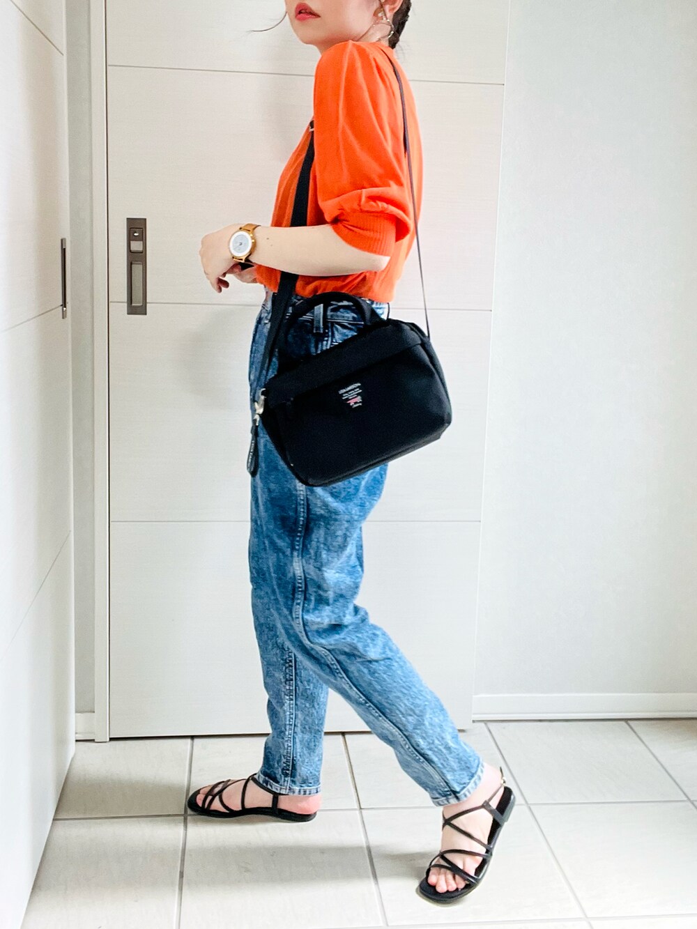 オレンジ系のニット/セーター、ブルー系のデニムパンツ、ブラック系のサンダルを着用したレディースの夏コーディネートの4枚目の写真