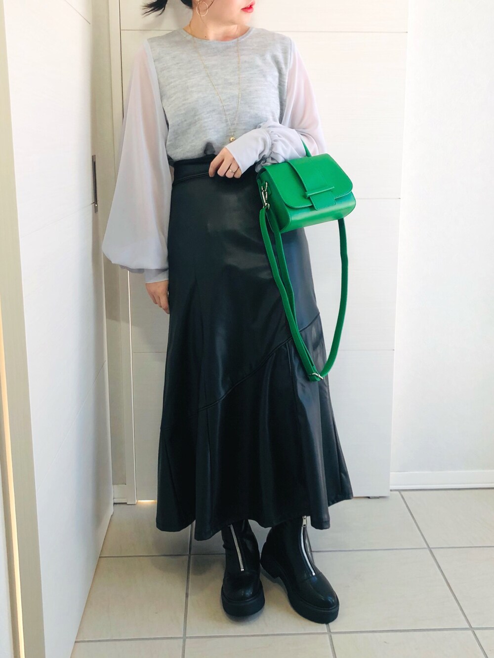 グレー系のTシャツ/カットソー、ブラック系のスカート、ブラック系のブーツを着用したレディースの冬コーディネートの2枚目の写真