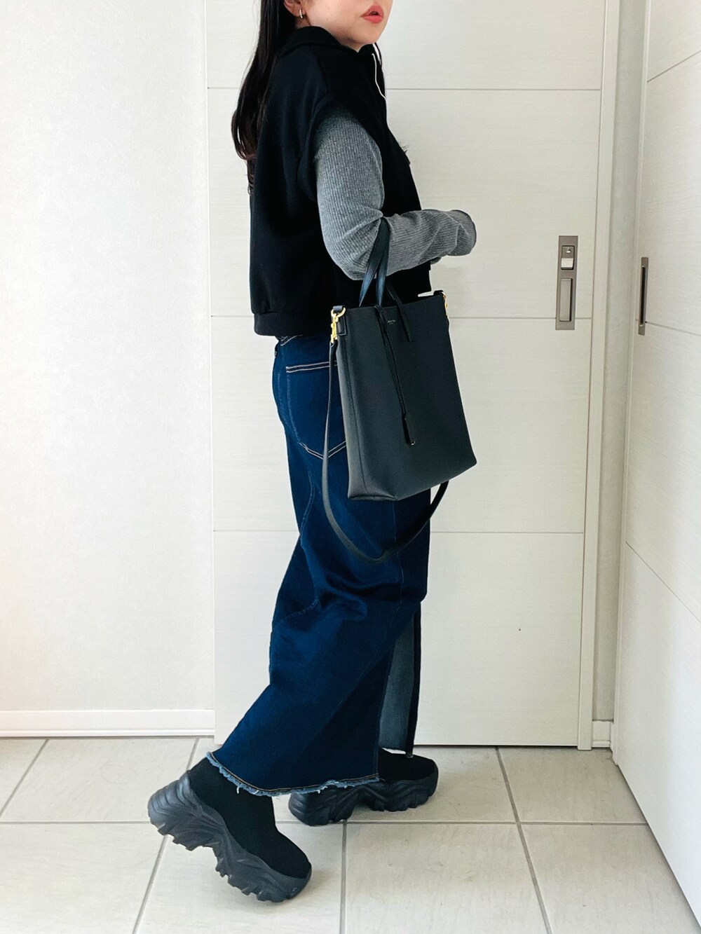 ブラック系のベスト、グレー系のTシャツ/カットソー、ブルー系のデニムスカートを着用したレディースの秋コーディネートの5枚目の写真