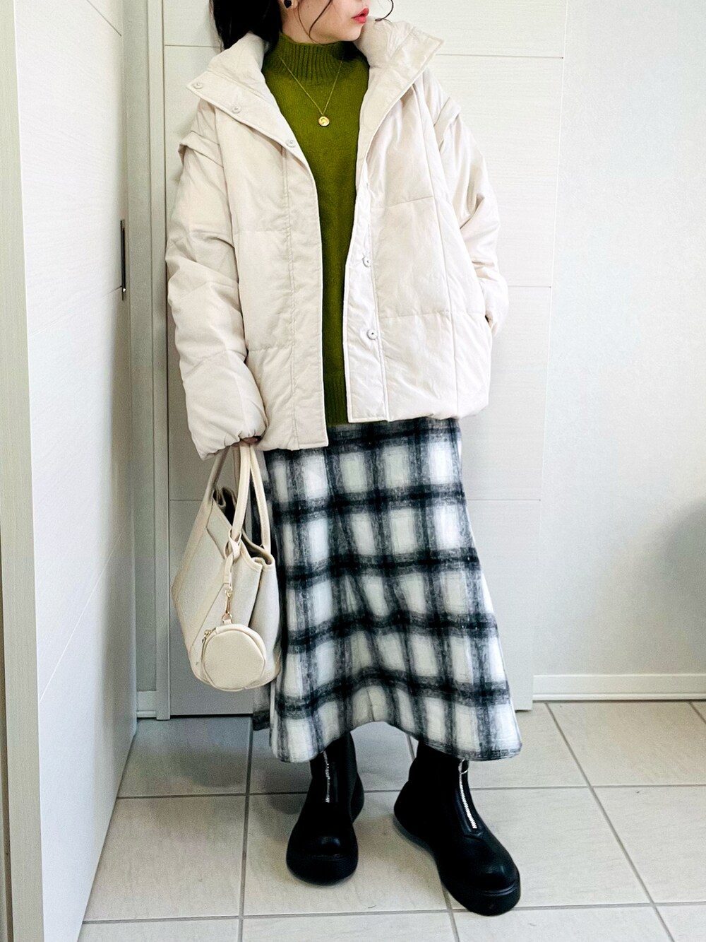 ホワイト系のダウンジャケット/コート、グリーン系のニット/セーター、ホワイト系のスカートを着用したレディースの冬コーディネートの3枚目の写真