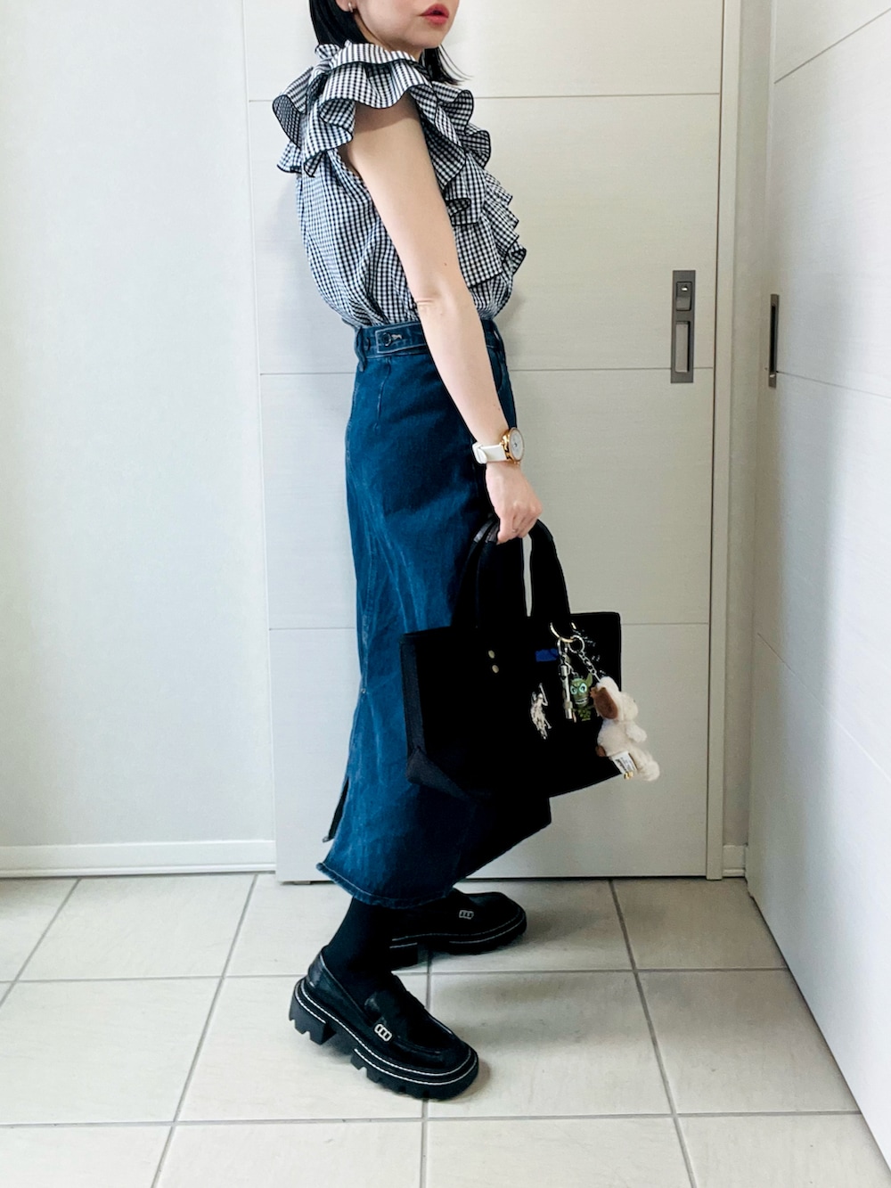 ブラック系のシャツ/ブラウス、ブルー系のデニムスカート、ブラック系のローファーを着用したレディースの春コーディネートの4枚目の写真