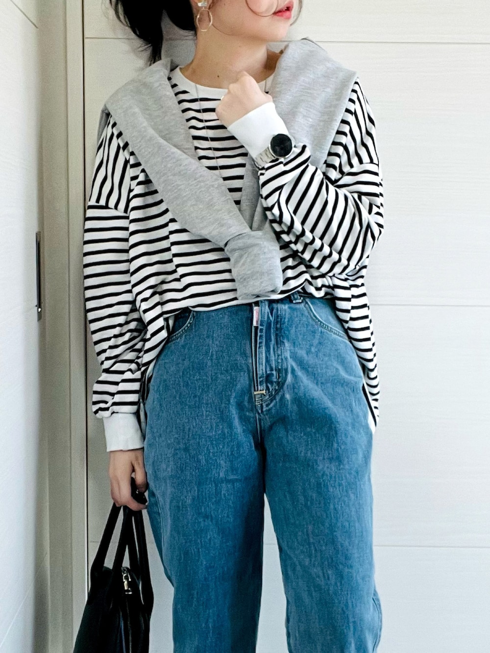 ブラック系のTシャツ/カットソー、グレー系のカーディガン/ボレロ、ブルー系のデニムパンツを着用したレディースの春コーディネートの2枚目の写真