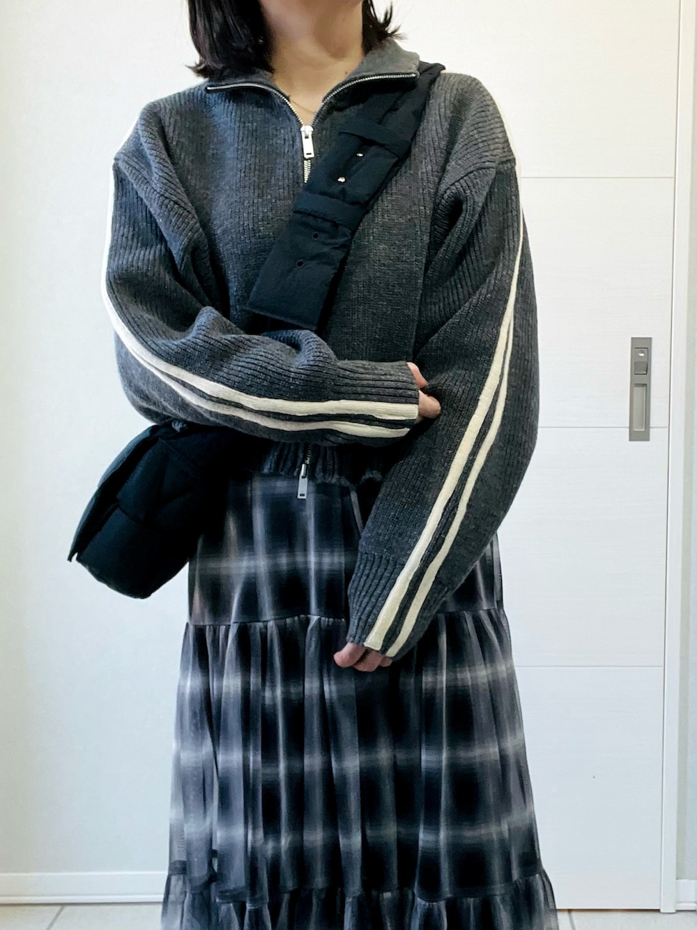 グレー系のニット/セーター、ブラック系のスカート、ブラック系のスニーカーを着用したレディースの冬コーディネートの2枚目の写真