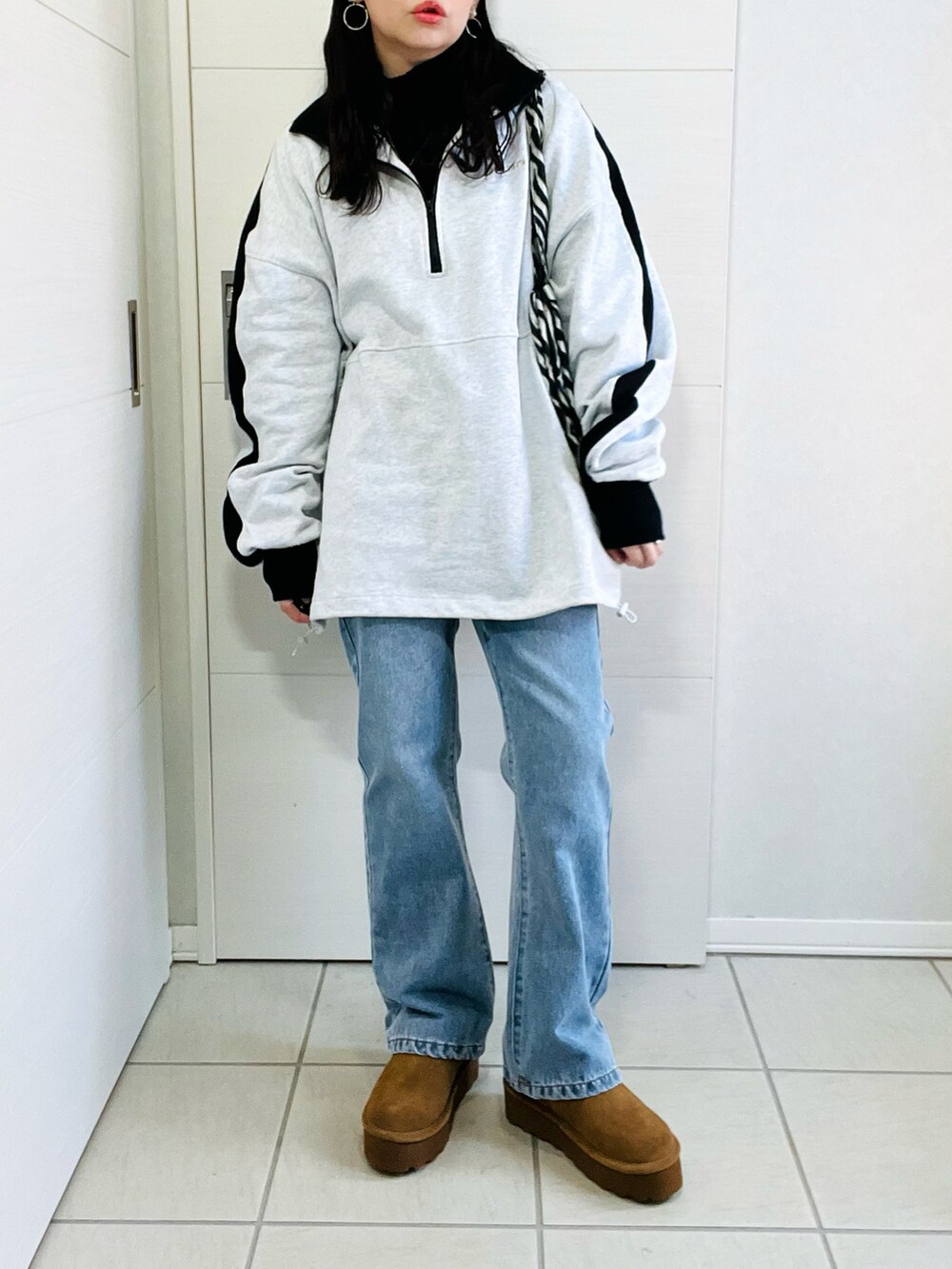 グレー系のスウェット、ブルー系のデニムパンツ、ブラウン系のブーツを着用したレディースの冬コーディネートの5枚目の写真