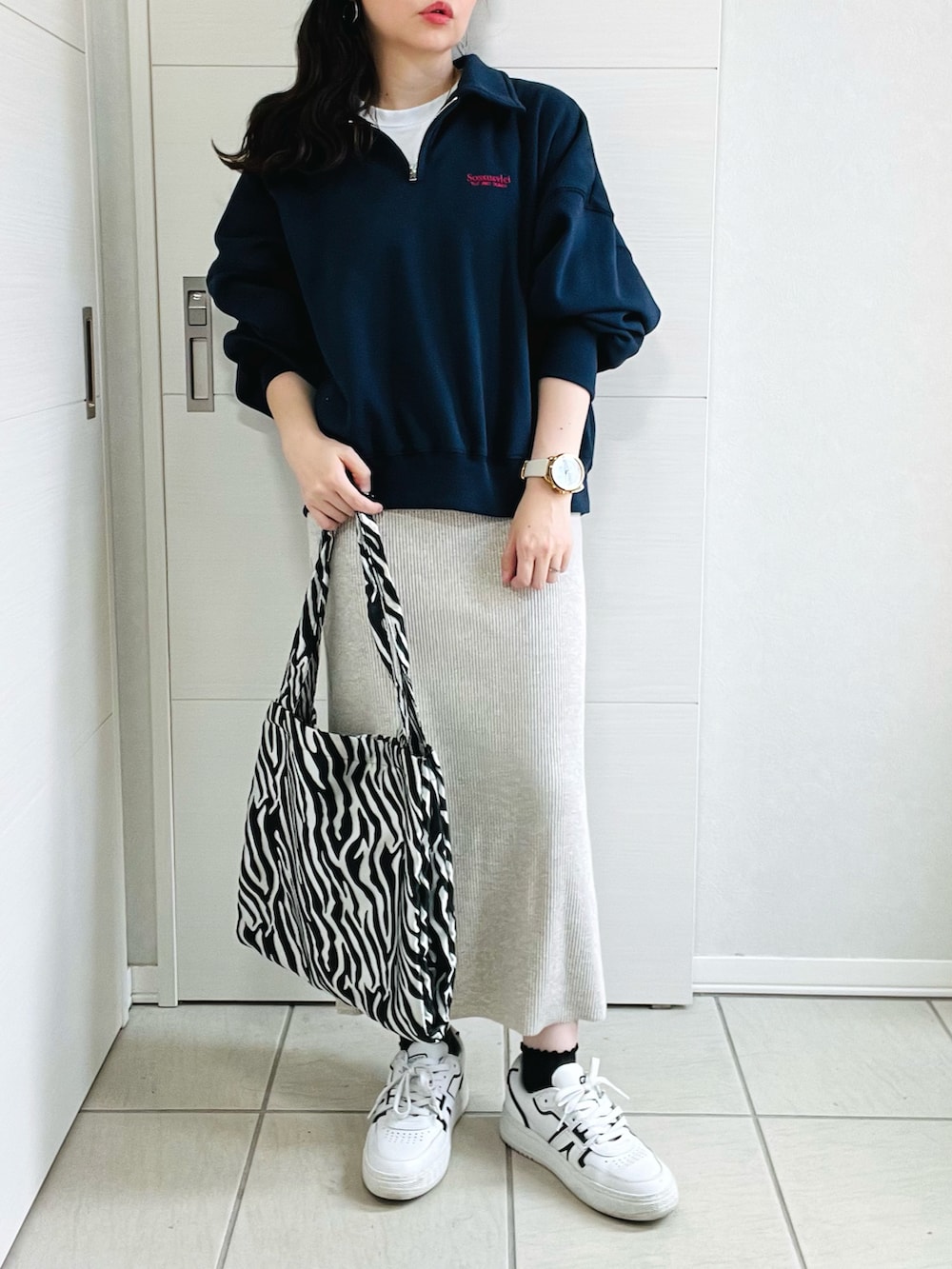 ブルー系のスウェット、ベージュ系のスカート、ホワイト系のスニーカーを着用したレディースの秋コーディネートの2枚目の写真
