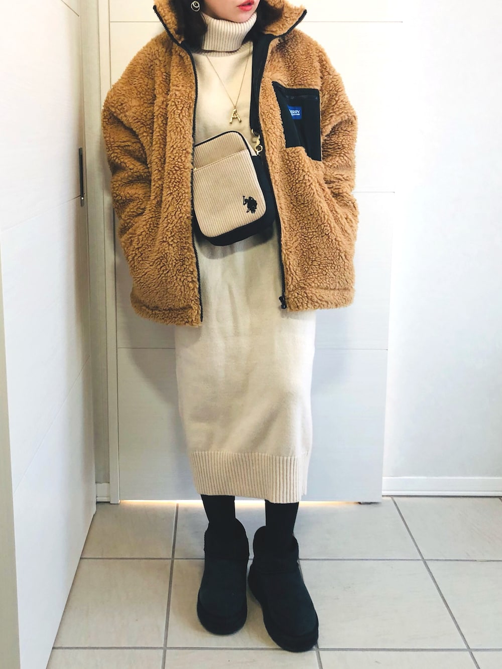 ベージュ系のブルゾン、ホワイト系のワンピース、ブラック系のブーツを着用したレディースの冬コーディネートの2枚目の写真