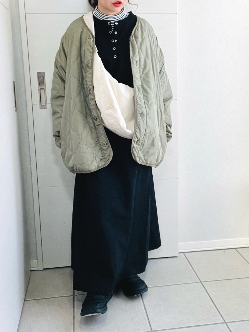 ブラック系のワンピース、ホワイト系のショルダーバッグ、グリーン系のノーカラージャケットを着用したレディースの冬コーディネートの5枚目の写真