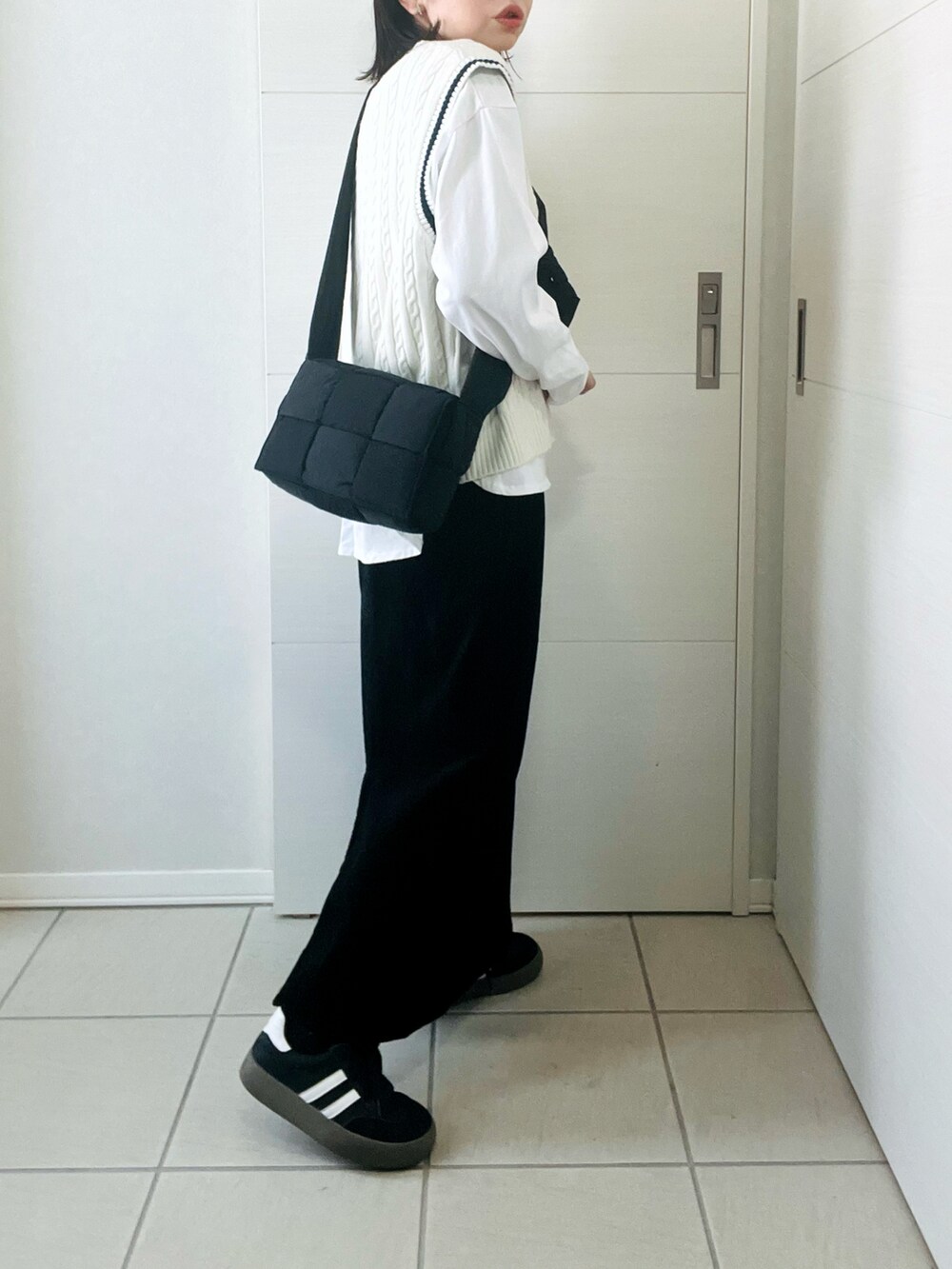 ホワイト系のTシャツ/カットソー、ホワイト系のベスト、ブラック系のスカートを着用したレディースの冬コーディネートの4枚目の写真