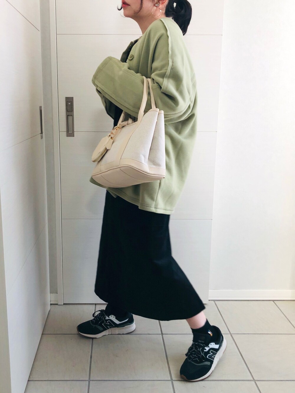 グリーン系のカーディガン/ボレロ、ブラック系のTシャツ/カットソー、ブラック系のジャンパースカートを着用したレディースの冬コーディネートの3枚目の写真