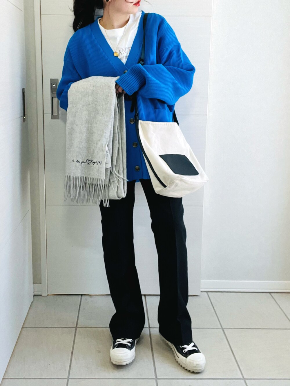 ブルー系のカーディガン/ボレロ、ホワイト系のTシャツ/カットソー、ブラック系のスラックスを着用したレディースの春コーディネートの4枚目の写真