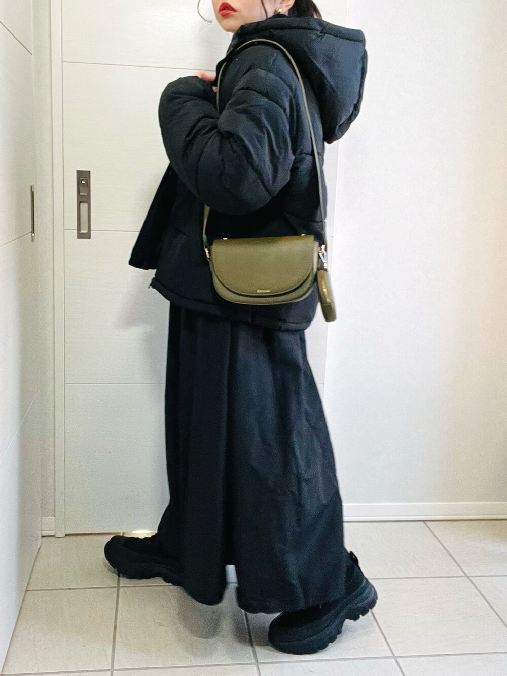 グレー系のワンピース、グリーン系のショルダーバッグ、ブラック系のスニーカーを着用したレディースの冬コーディネートの5枚目の写真