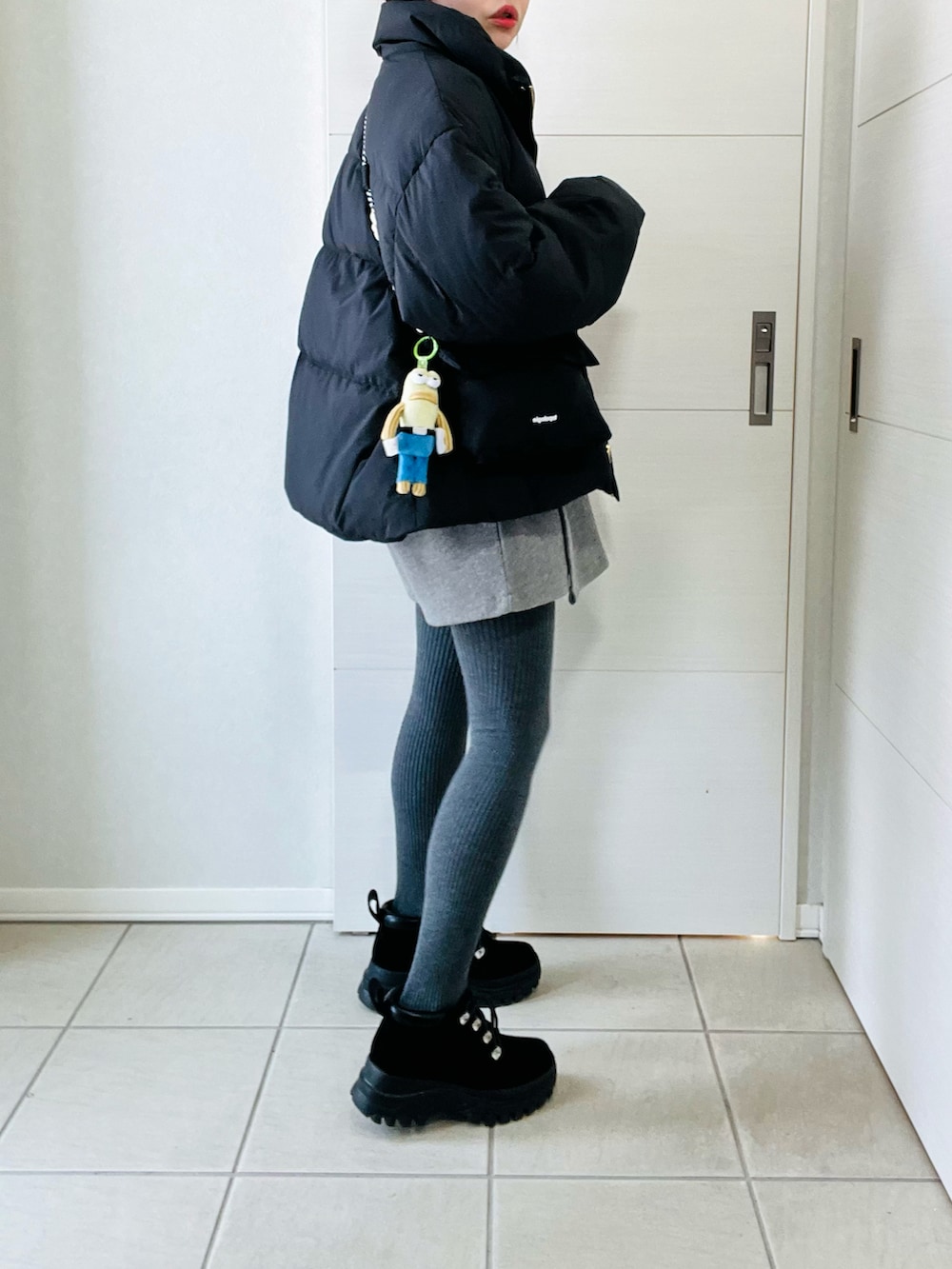 ブラック系のダウンジャケット/コート、ブラック系のブーツ、ホワイト系のカーディガン/ボレロを着用したレディースの春コーディネートの5枚目の写真