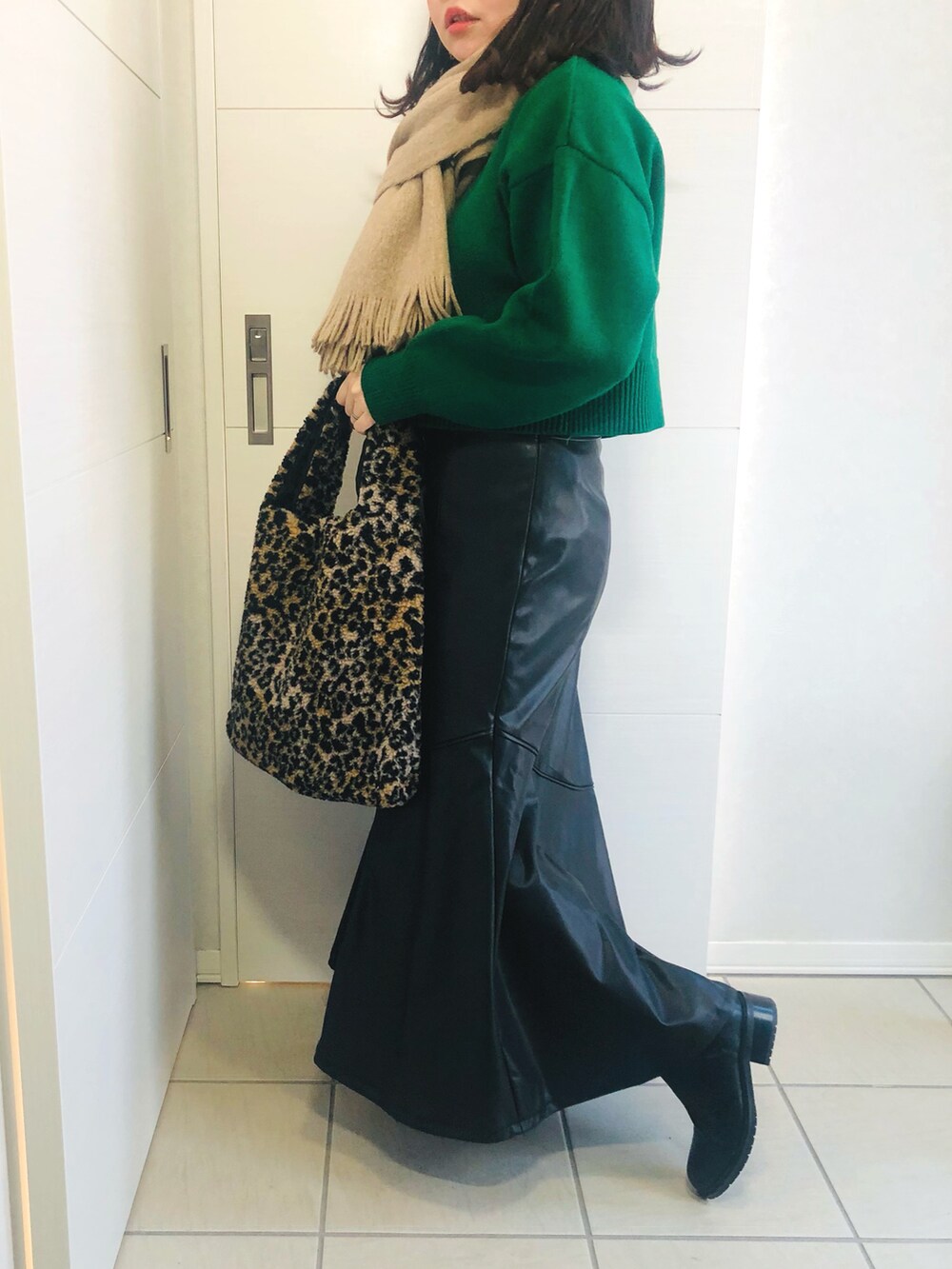 グリーン系のカーディガン/ボレロ、ブラック系のスカート、ブラック系のブーツを着用したレディースの冬コーディネートの3枚目の写真