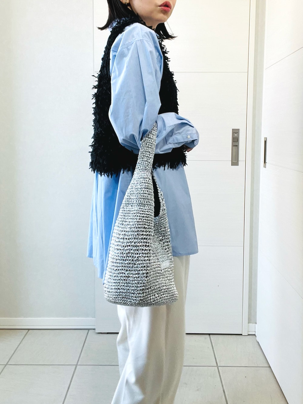 ブラック系のベスト、ブルー系のシャツ/ブラウス、ホワイト系のスラックスを着用したレディースの春コーディネートの3枚目の写真