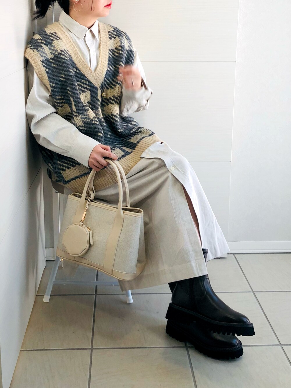 ベージュ系のワンピース、ホワイト系のベスト、ブラウン系のブーツを着用したレディースの冬コーディネートの2枚目の写真