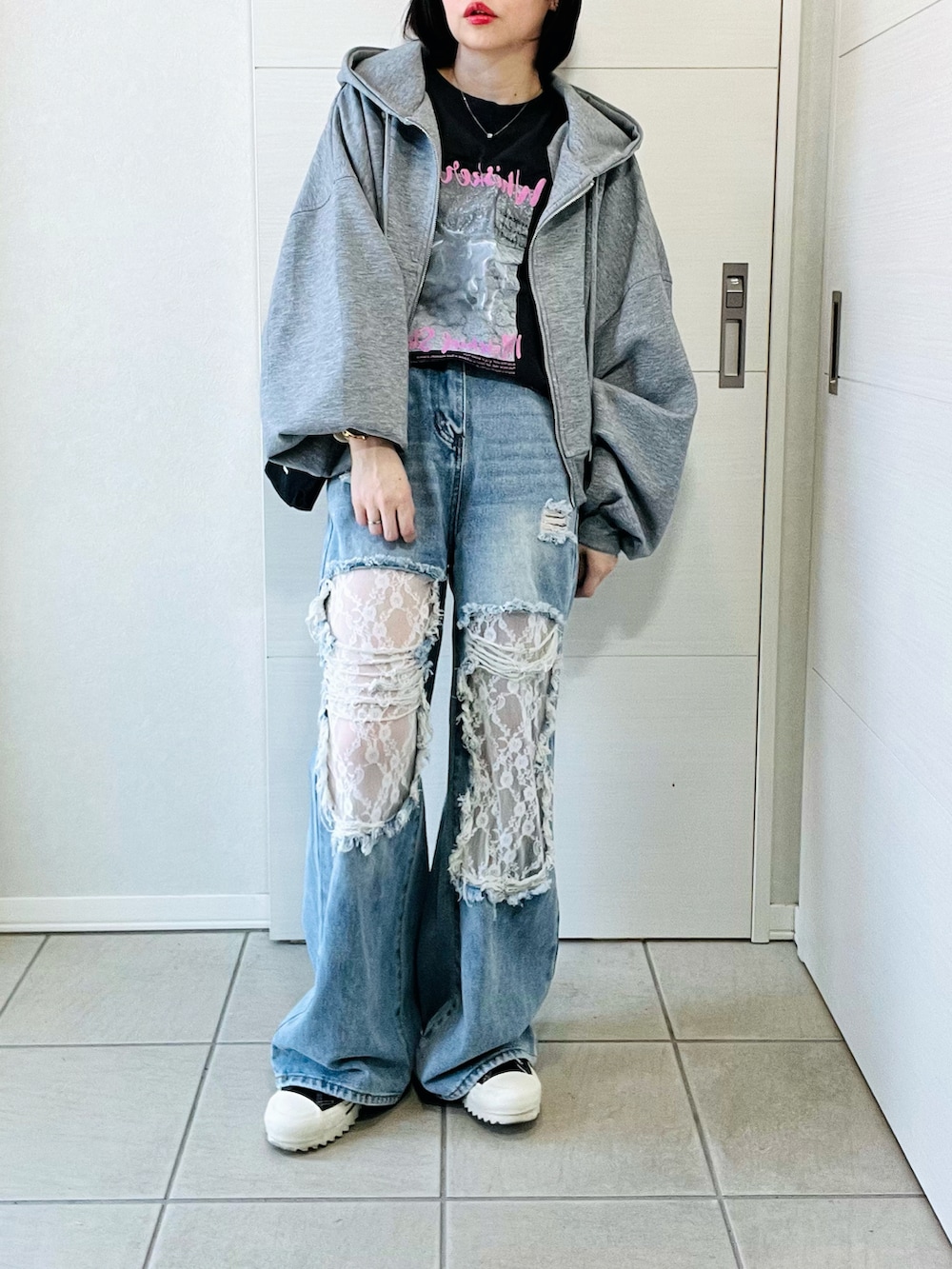 グレー系のパーカー、グレー系のTシャツ/カットソー、ブルー系のデニムパンツを着用したレディースの冬コーディネートの4枚目の写真