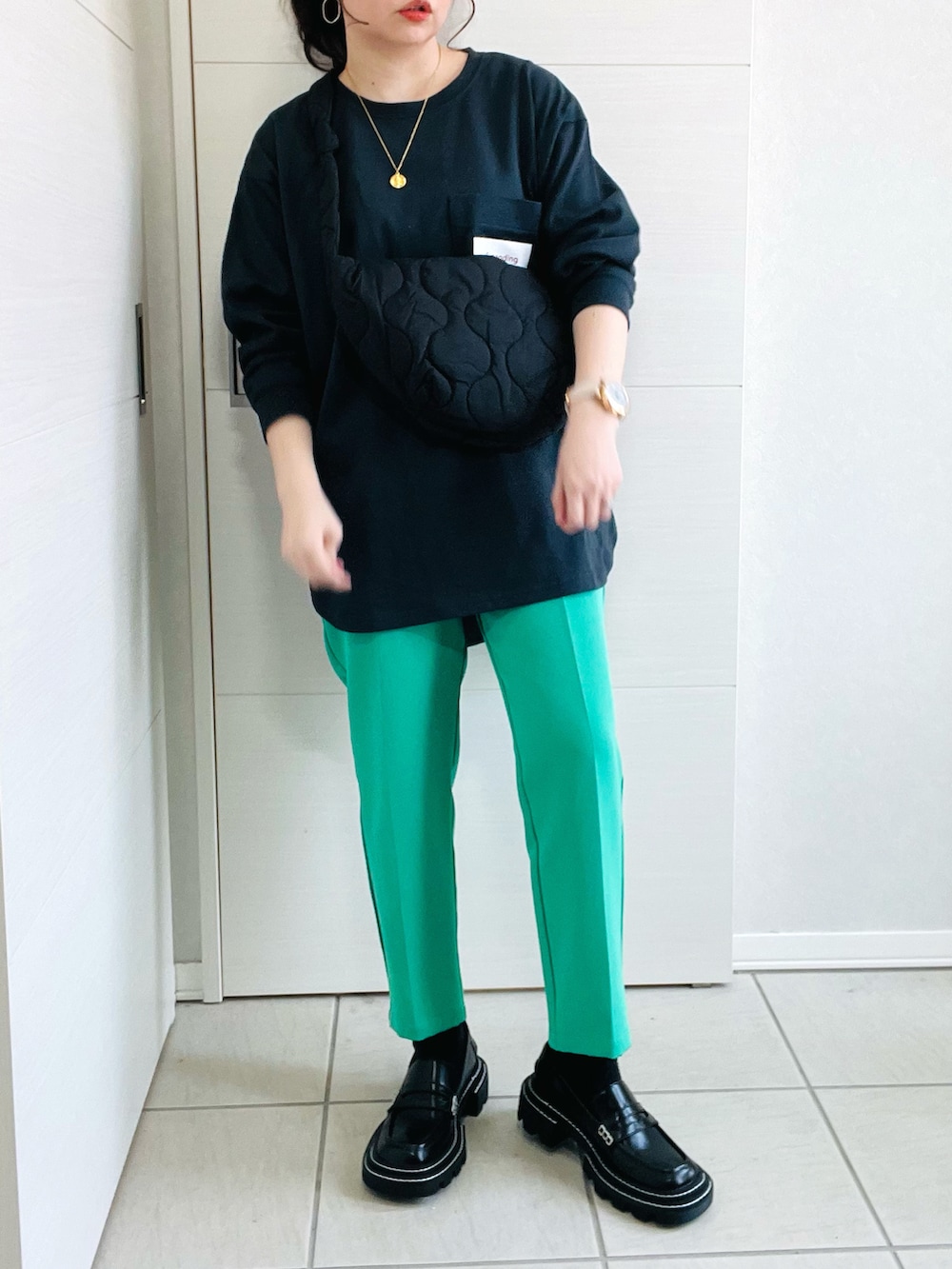 ブラック系のTシャツ/カットソー、グリーン系のスラックス、ブラック系のローファーを着用したレディースの春コーディネートの2枚目の写真