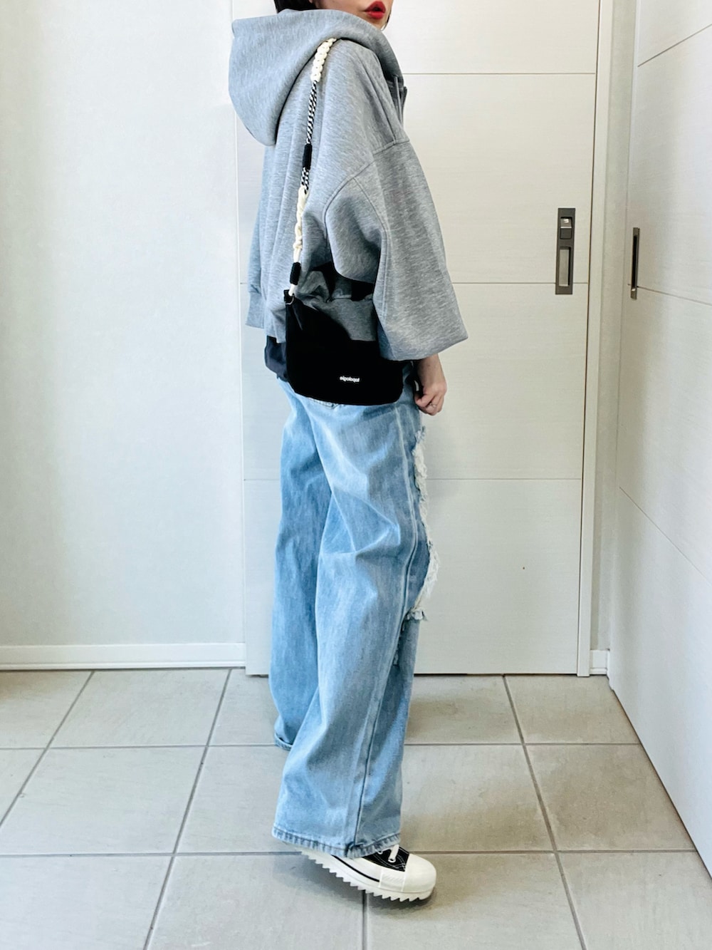 グレー系のパーカー、グレー系のTシャツ/カットソー、ブルー系のデニムパンツを着用したレディースの冬コーディネートの5枚目の写真