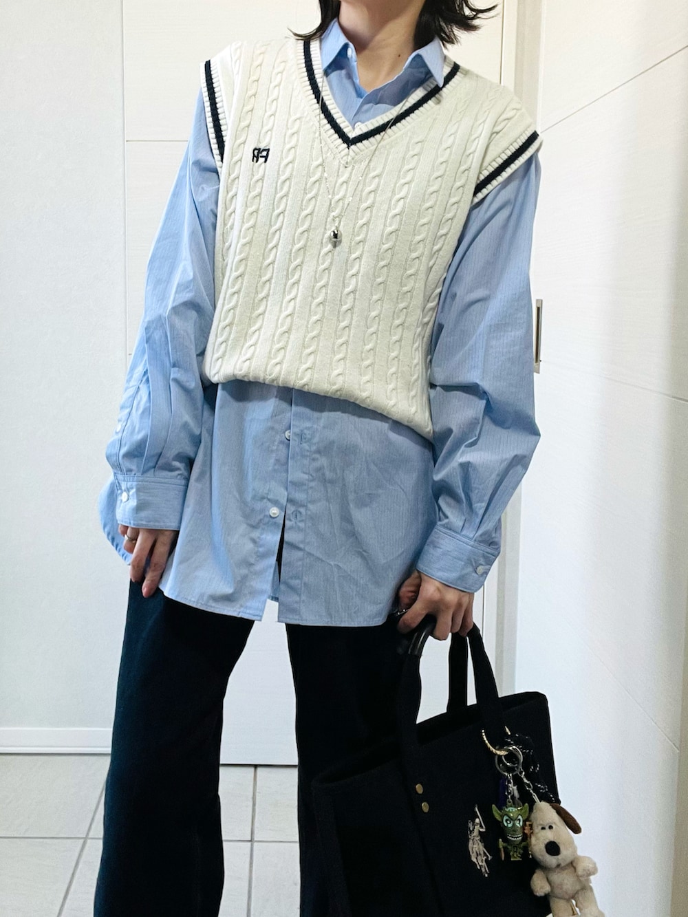 ホワイト系のベスト、ブルー系のシャツ/ブラウス、ブルー系のデニムパンツを着用したレディースの春コーディネートの2枚目の写真