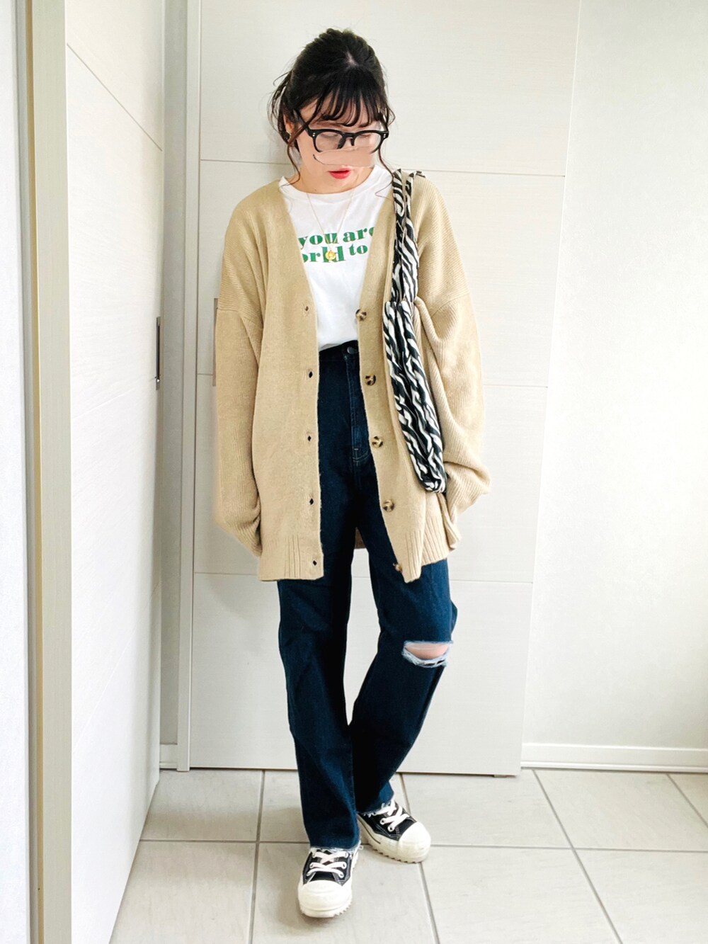 ベージュ系のカーディガン/ボレロ、ホワイト系のTシャツ/カットソー、ブルー系のデニムパンツを着用したレディースの秋コーディネートの2枚目の写真