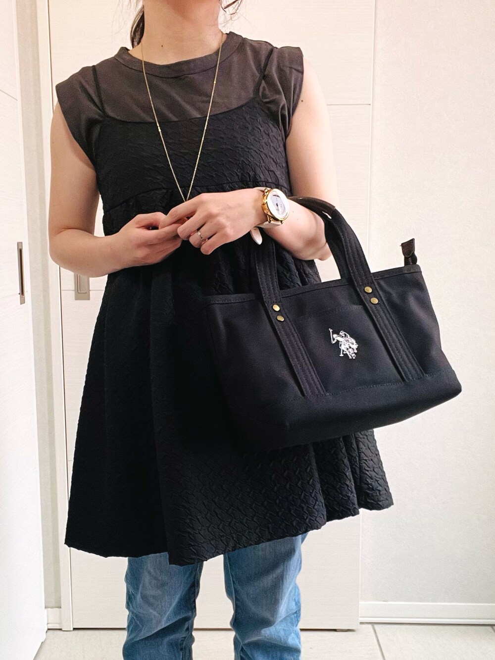 ブラック系のトートバッグ、ブラック系のワンピース、ブルー系のデニムパンツを着用したレディースの夏コーディネートの4枚目の写真