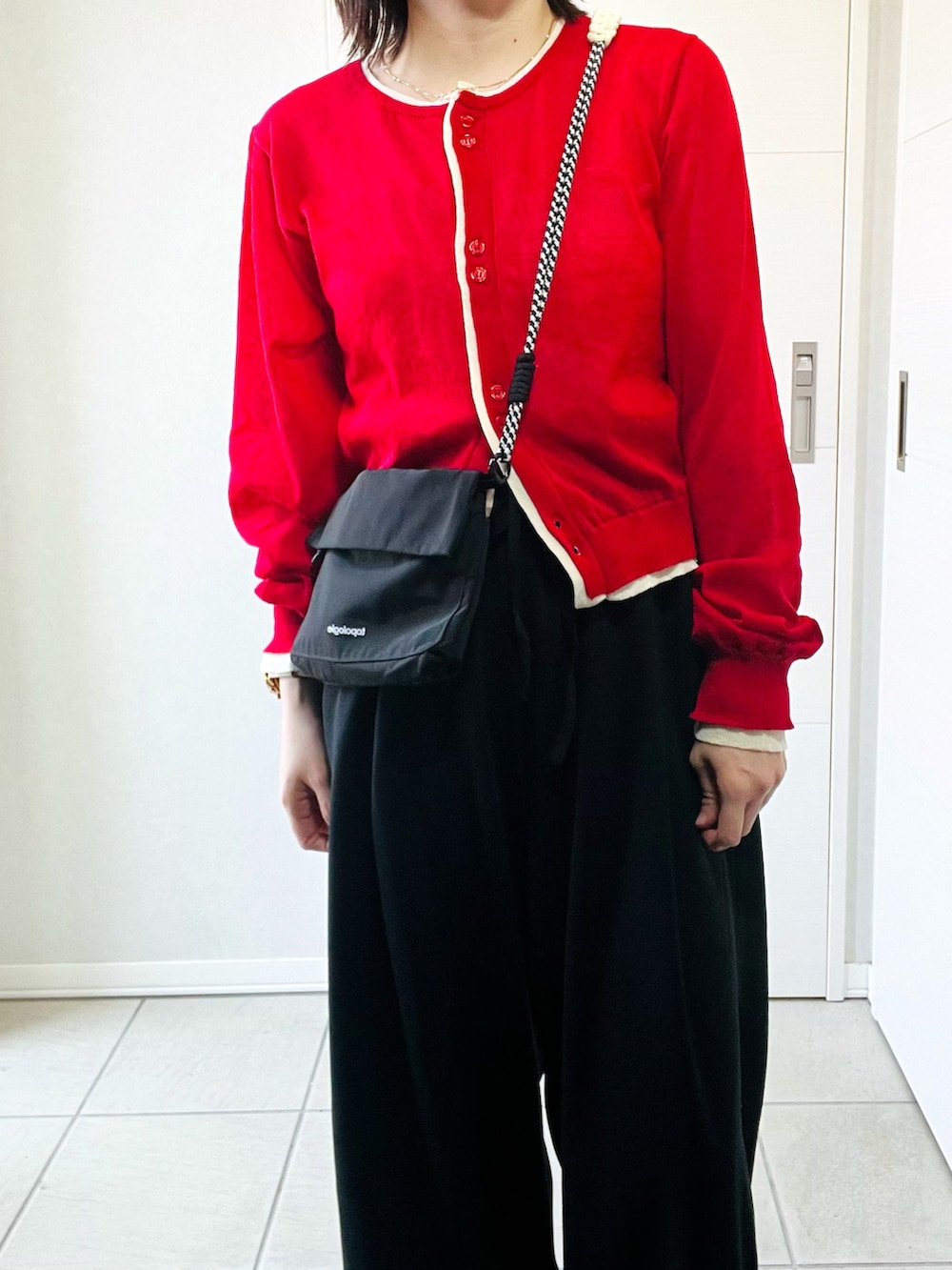 レッド系のカーディガン/ボレロ、ブラック系のその他パンツ、グレー系のスニーカーを着用したレディースの春コーディネートの2枚目の写真