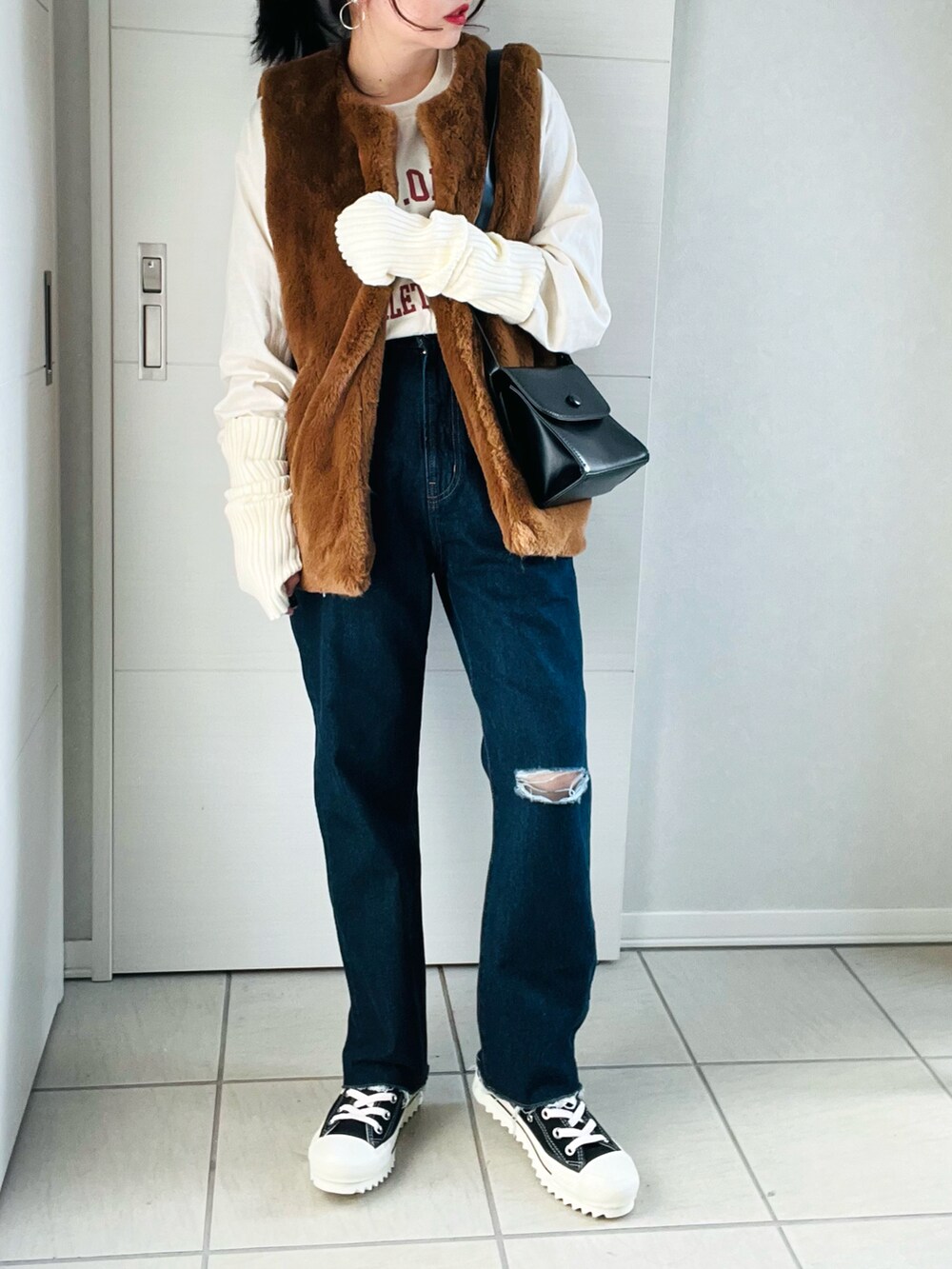 ベージュ系のTシャツ/カットソー、ブラウン系のベスト、ブルー系のデニムパンツを着用したレディースの秋コーディネートの2枚目の写真