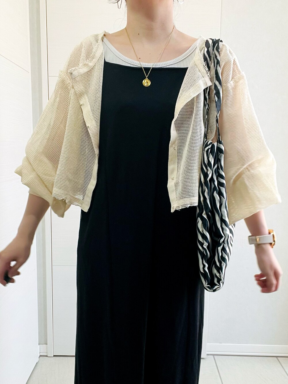 ホワイト系のカーディガン/ボレロ、ブラック系のワンピース、ベージュ系のパンプスを着用したレディースの春コーディネートの3枚目の写真