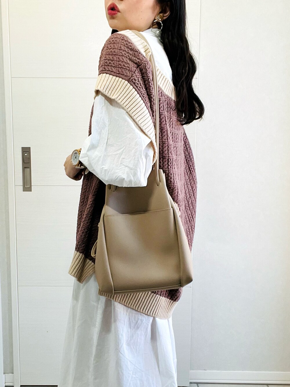 ブラウン系のベスト、ホワイト系のワンピース、ベージュ系のスニーカーを着用したレディースの秋コーディネートの4枚目の写真