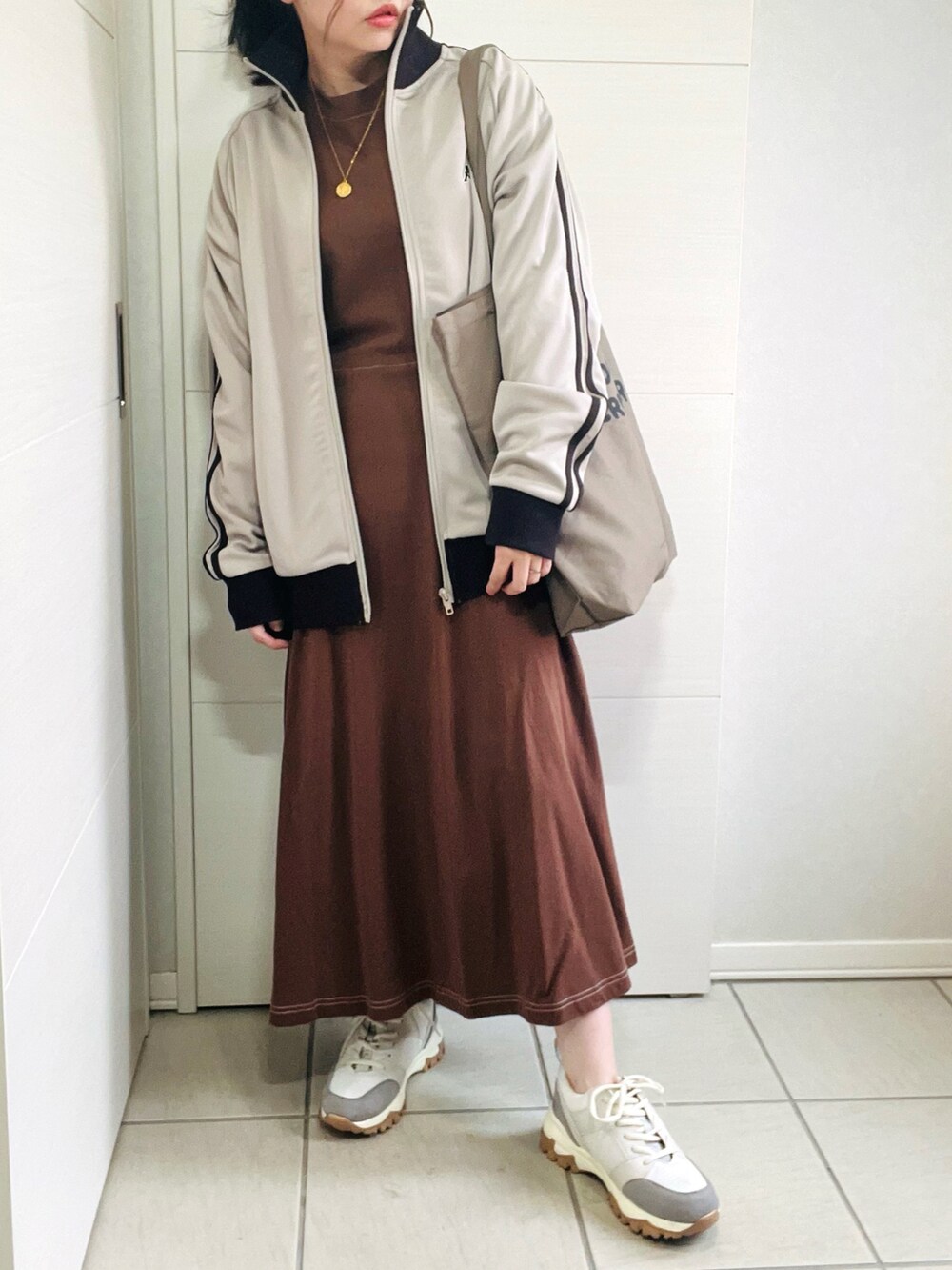 ベージュ系のジャージ、ブラウン系のワンピース、ベージュ系のスニーカーを着用したレディースの秋コーディネートの4枚目の写真