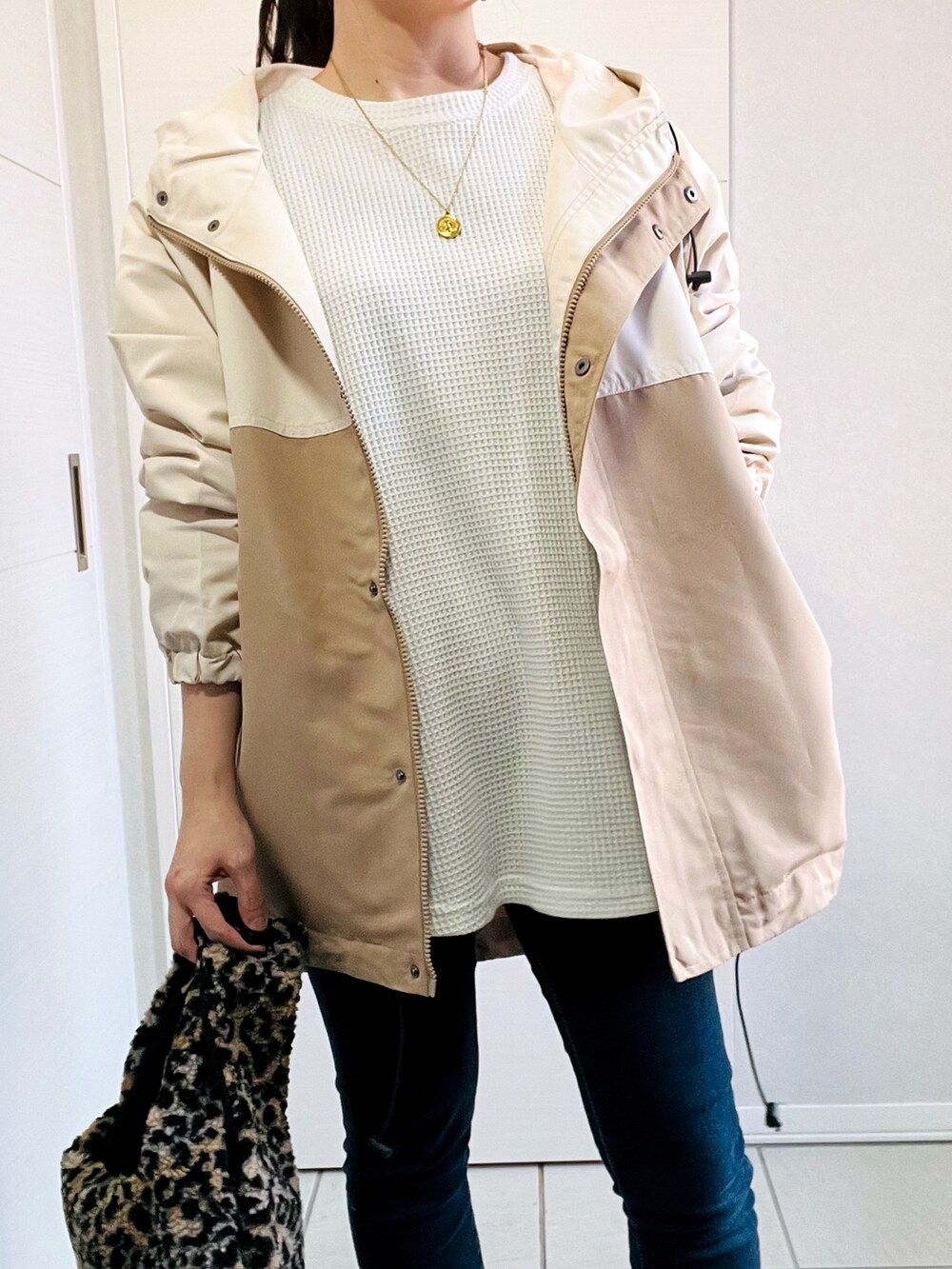 ベージュ系のマウンテンパーカー、ホワイト系のスウェット、ブルー系のデニムパンツを着用したレディースの秋コーディネートの2枚目の写真