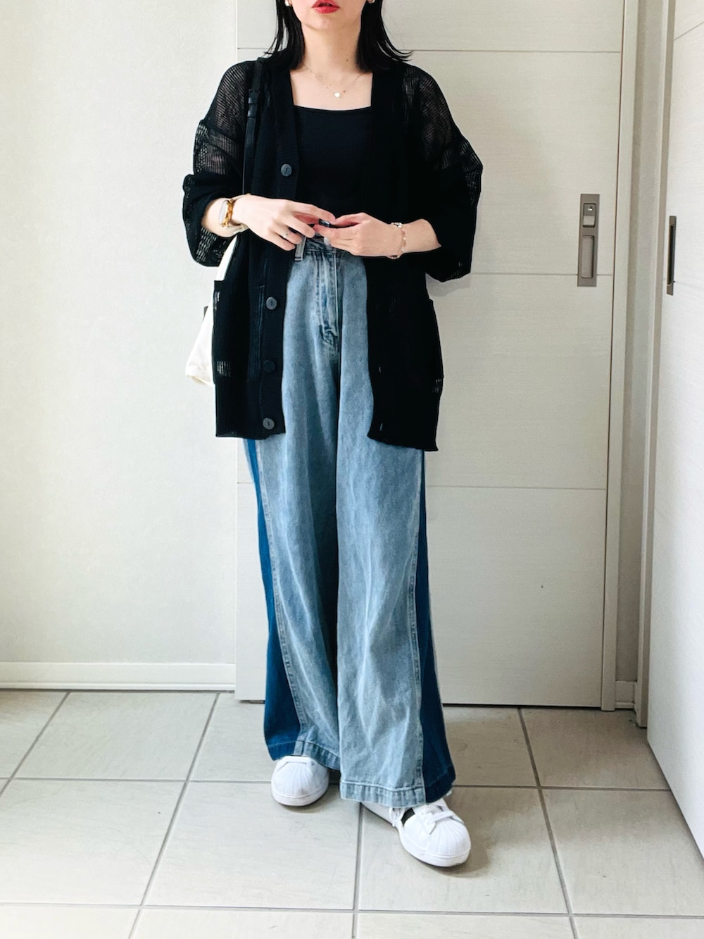 ブラック系のカーディガン/ボレロ、ブルー系のデニムパンツ、ホワイト系のスニーカーを着用したレディースの夏コーディネートの4枚目の写真