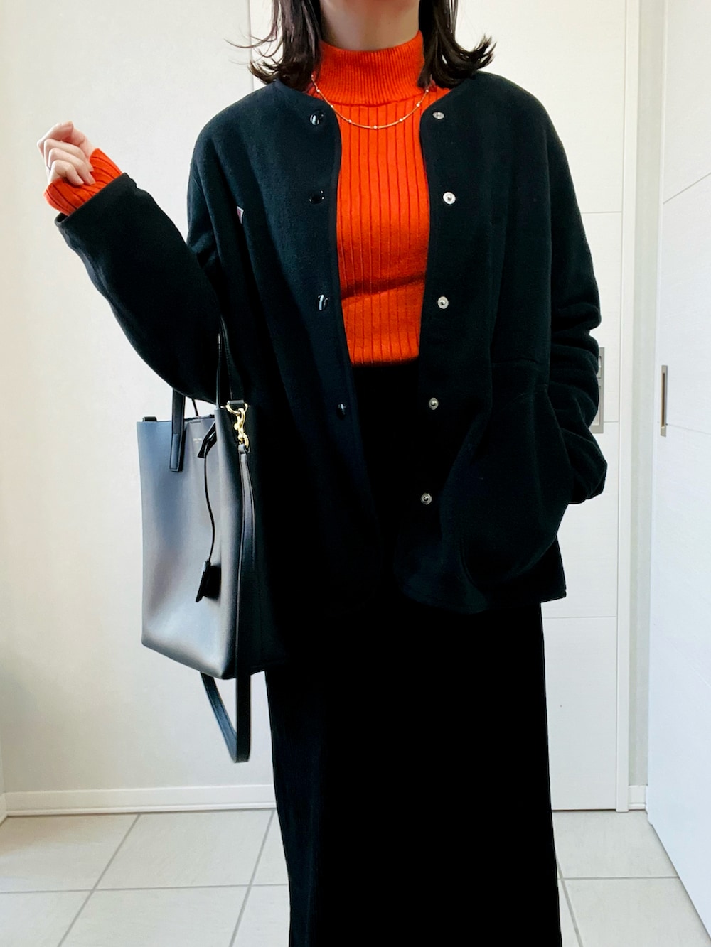 ブラック系のノーカラージャケット、ブラック系のスカート、ブラック系のブーツを着用したレディースの冬コーディネートの2枚目の写真