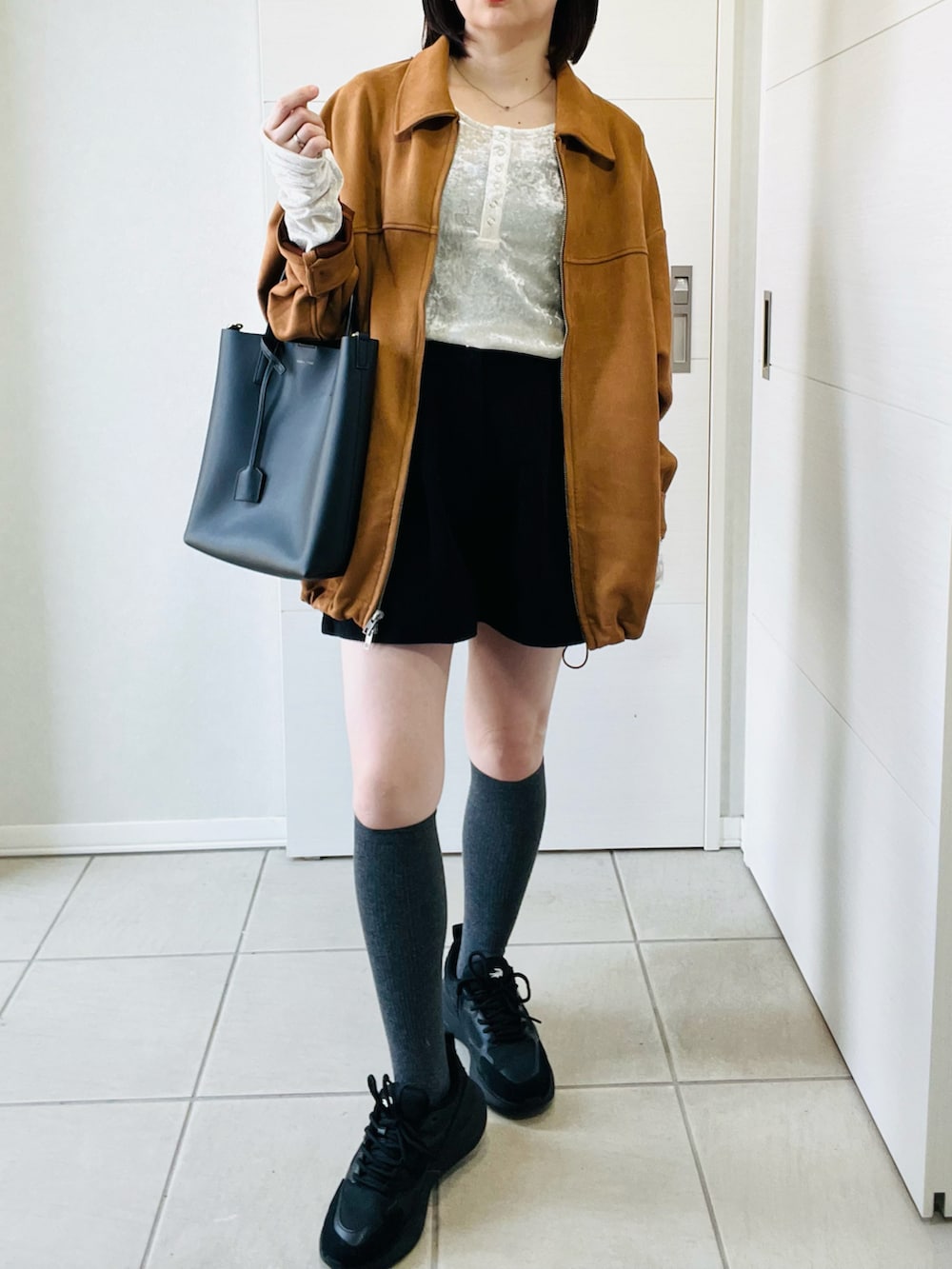 ホワイト系のTシャツ/カットソー、ベージュ系のブルゾン、ブラック系のスニーカーを着用したレディースの春コーディネートの4枚目の写真