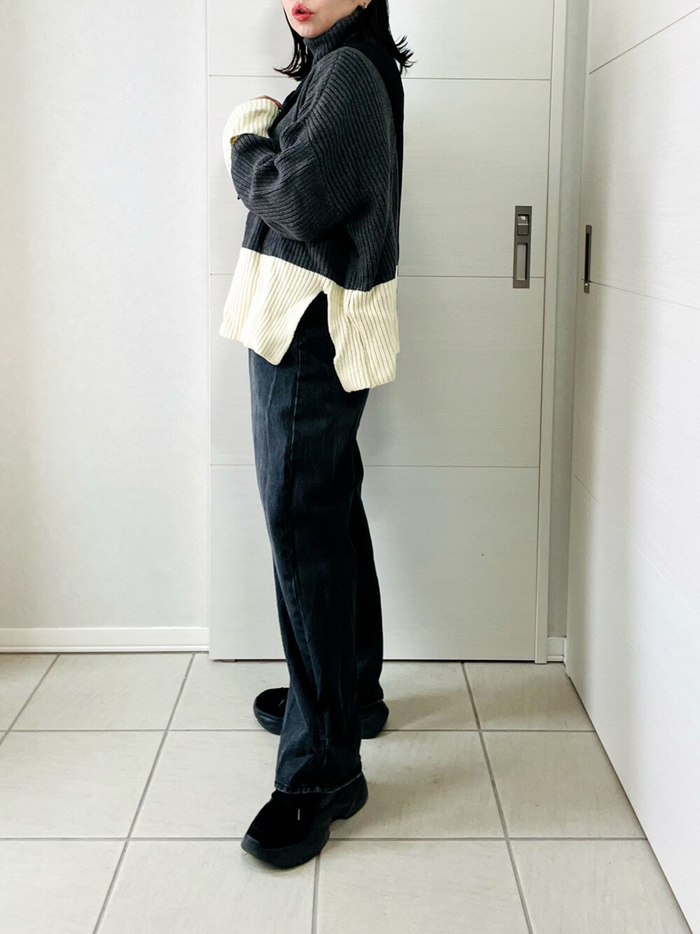 グレー系のニット/セーター、ブラック系のデニムパンツ、ブラック系のスニーカーを着用したレディースの冬コーディネートの4枚目の写真