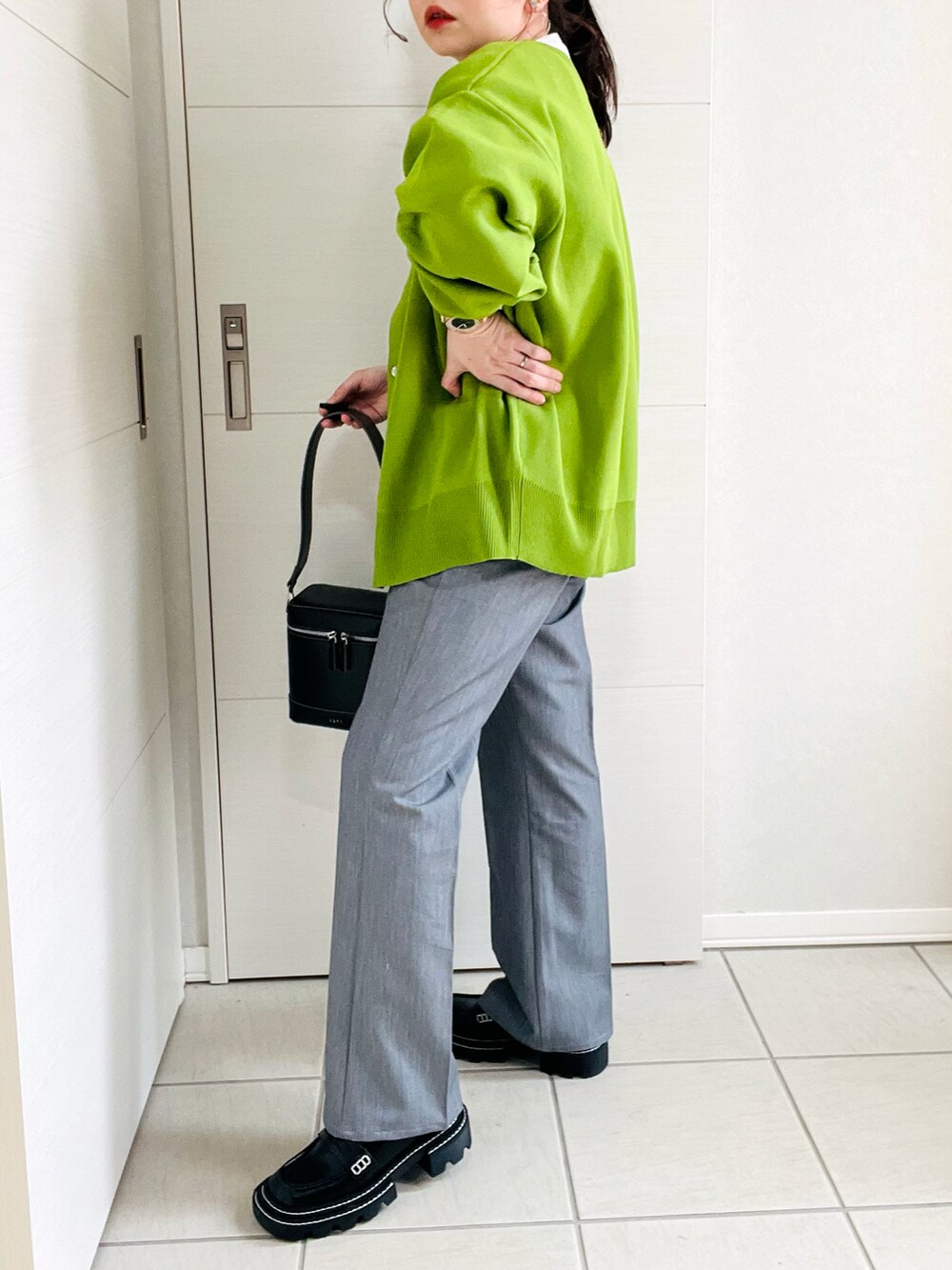 グリーン系のカーディガン/ボレロ、ホワイト系のTシャツ/カットソー、グレー系のスラックスを着用したレディースの春コーディネートの5枚目の写真