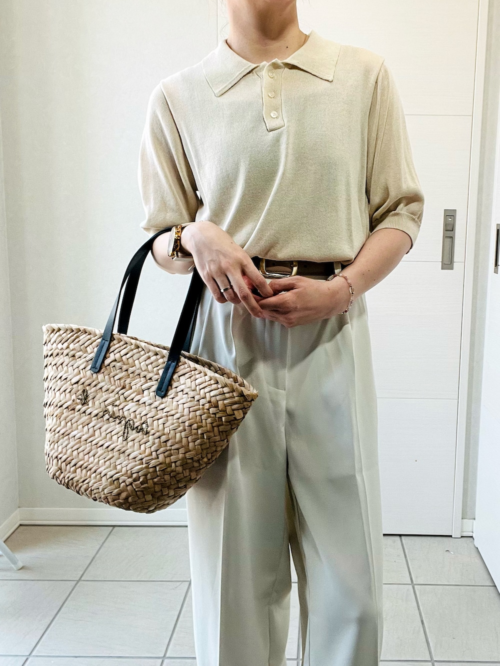 ホワイト系のポロシャツ、ホワイト系のスラックス、ブラック系のかごバッグを着用したレディースの夏コーディネートの2枚目の写真