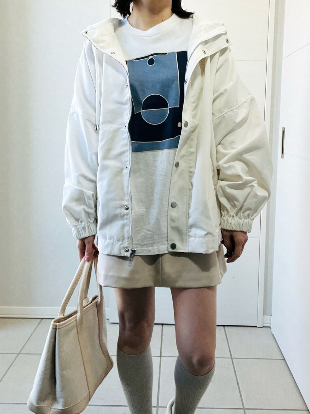 ホワイト系のマウンテンパーカー、ブルー系のTシャツ/カットソー、ホワイト系のスカートを着用したレディースの春コーディネートの2枚目の写真