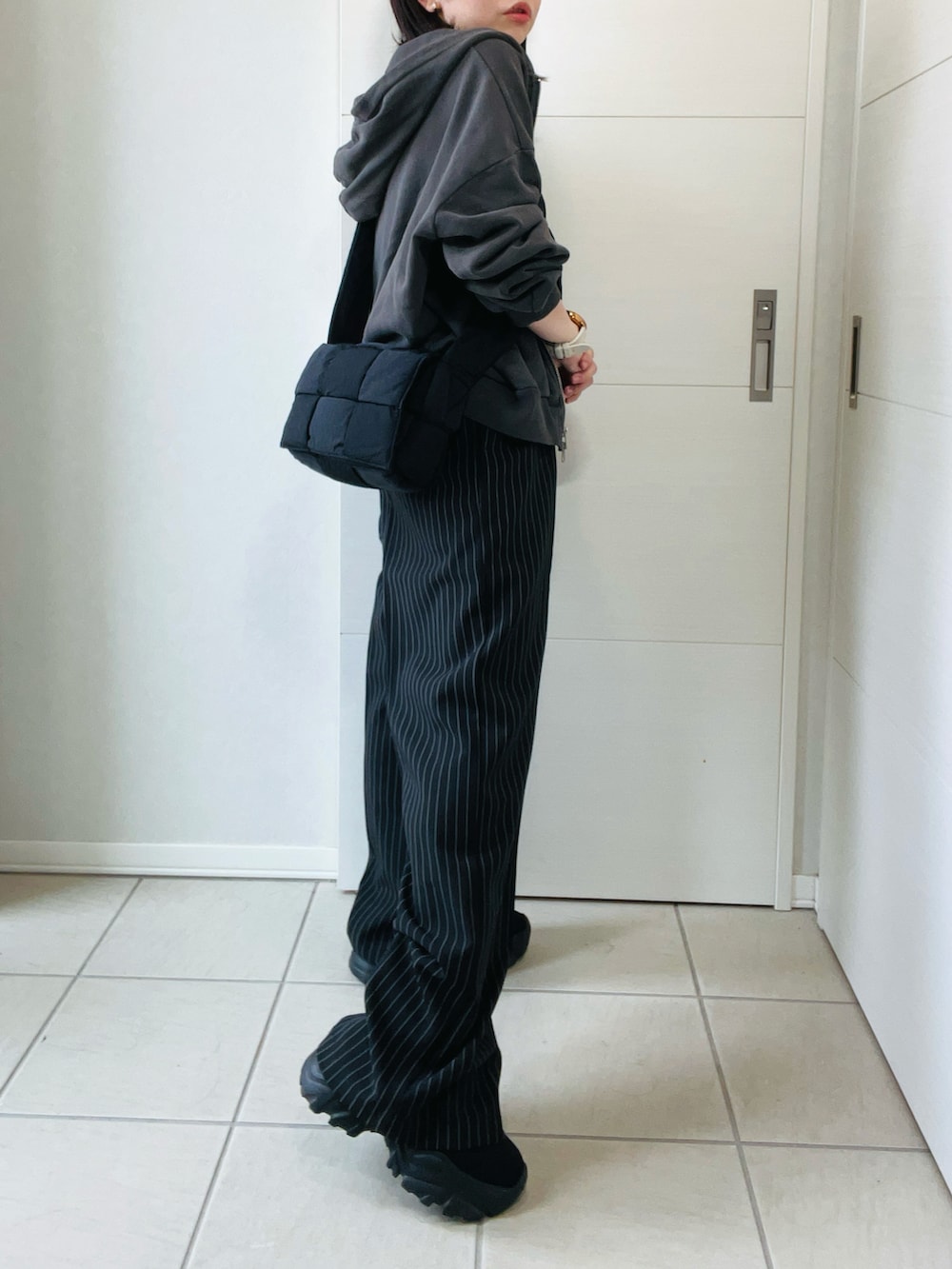 ブラック系のデニムパンツ、グレー系のパーカー、ブラック系のブーツを着用したレディースの秋コーディネートの5枚目の写真