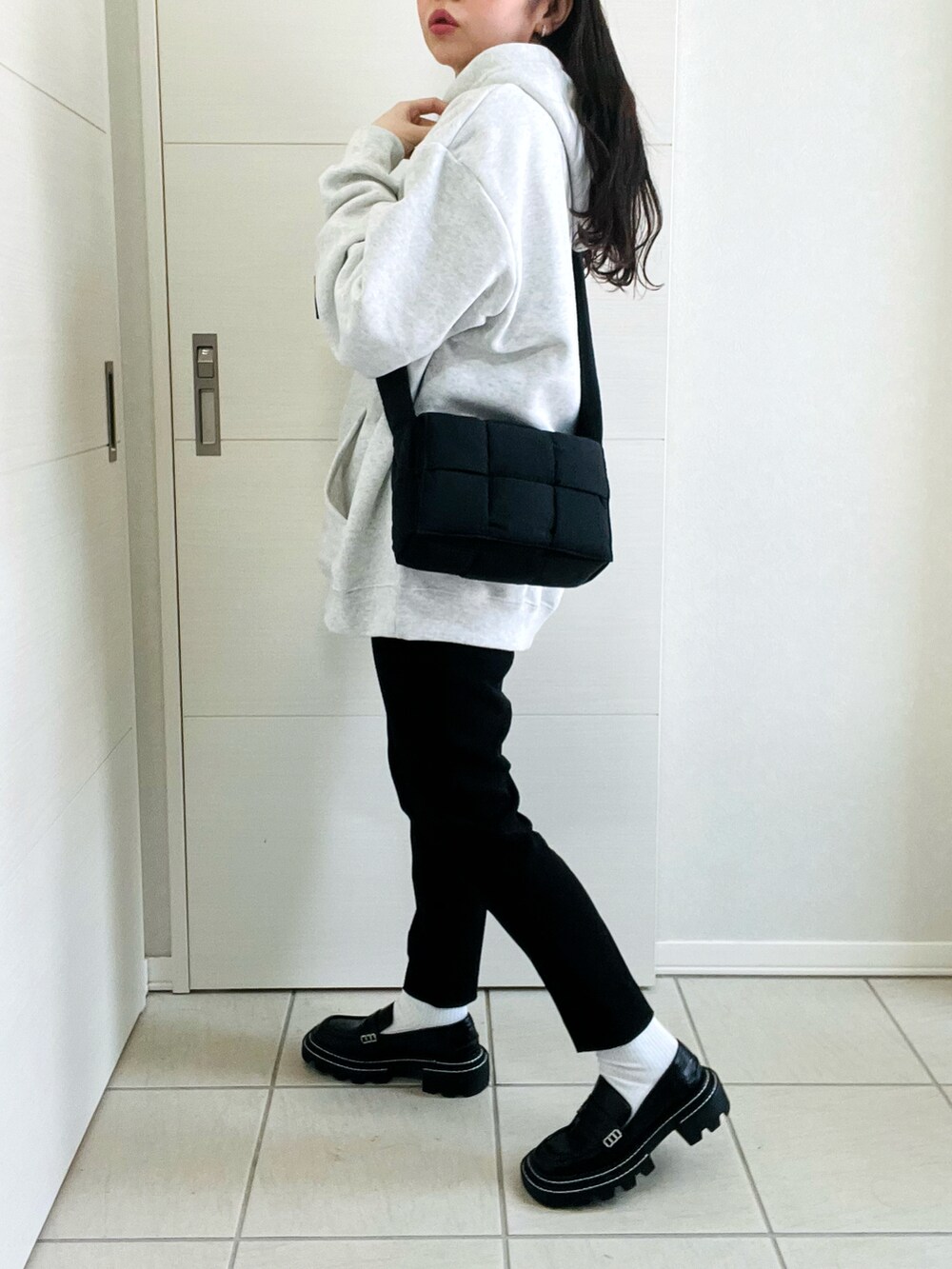 グレー系のパーカー、ブラック系のローファー、ブラック系のショルダーバッグを着用したレディースの春コーディネートの4枚目の写真