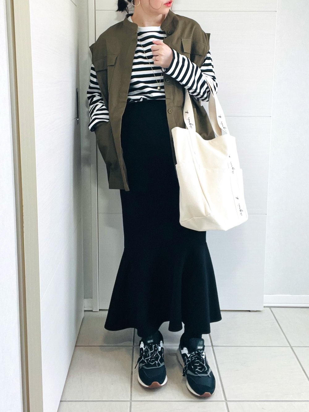 ブラック系のTシャツ/カットソー、グリーン系のベスト、ブラック系のセットアップを着用したレディースの春コーディネートの2枚目の写真