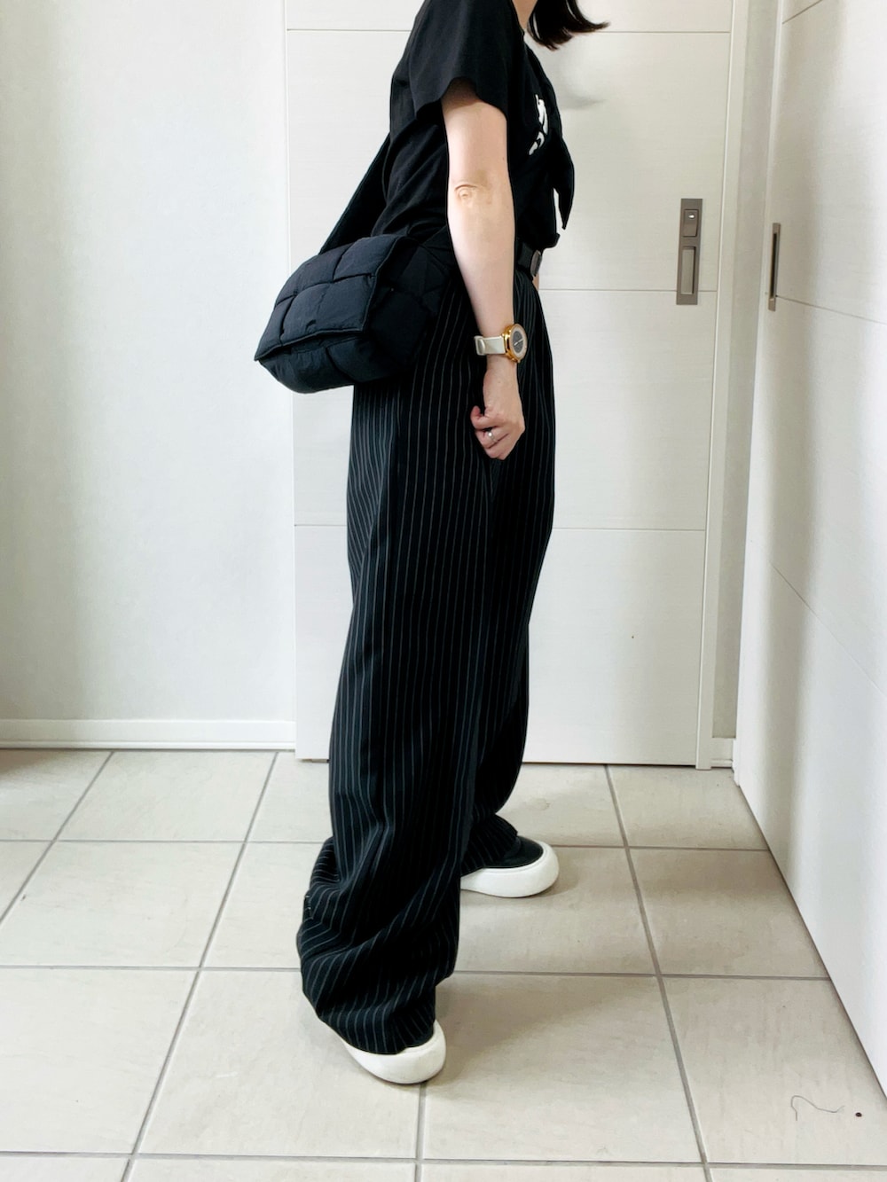 ブラック系のデニムパンツ、ブラック系のTシャツ/カットソー、ブラック系のスニーカーを着用したレディースの秋コーディネートの2枚目の写真
