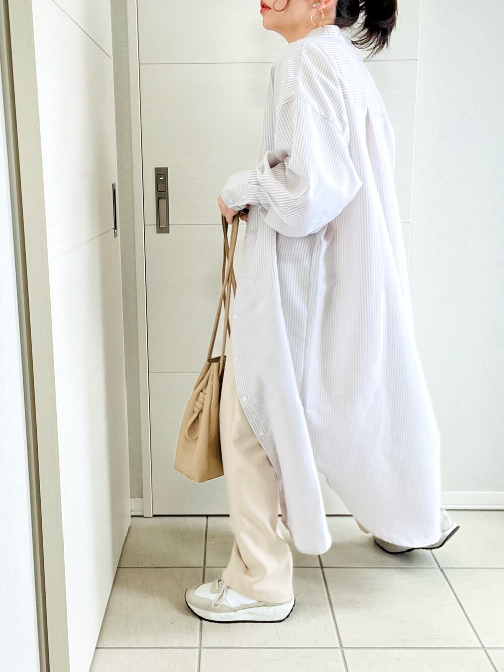 ベージュ系のシャツワンピース、ホワイト系のニット/セーター、ホワイト系のスラックスを着用したレディースの春コーディネートの3枚目の写真