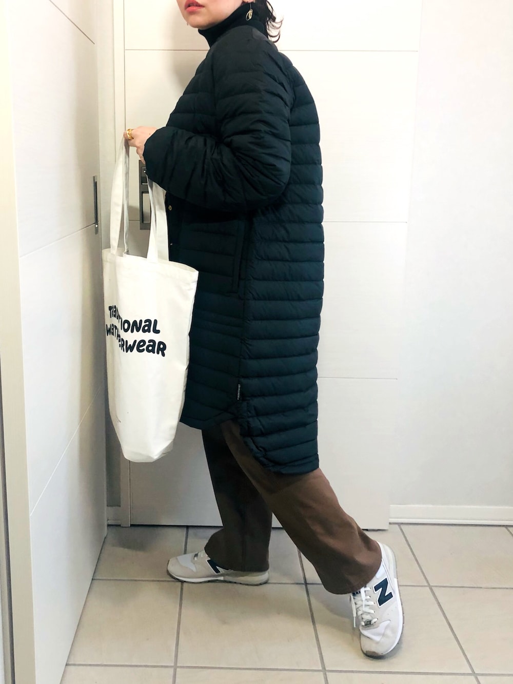 ブラック系のダウンジャケット/コート、ブラック系のニット/セーター、ブラウン系のチノパンツを着用したレディースの冬コーディネートの2枚目の写真