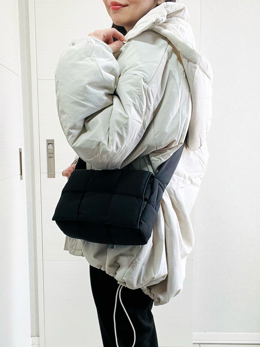 ホワイト系のダウンジャケット/コート、グレー系のニット/セーター、ブラック系のスラックスを着用したレディースの冬コーディネートの3枚目の写真