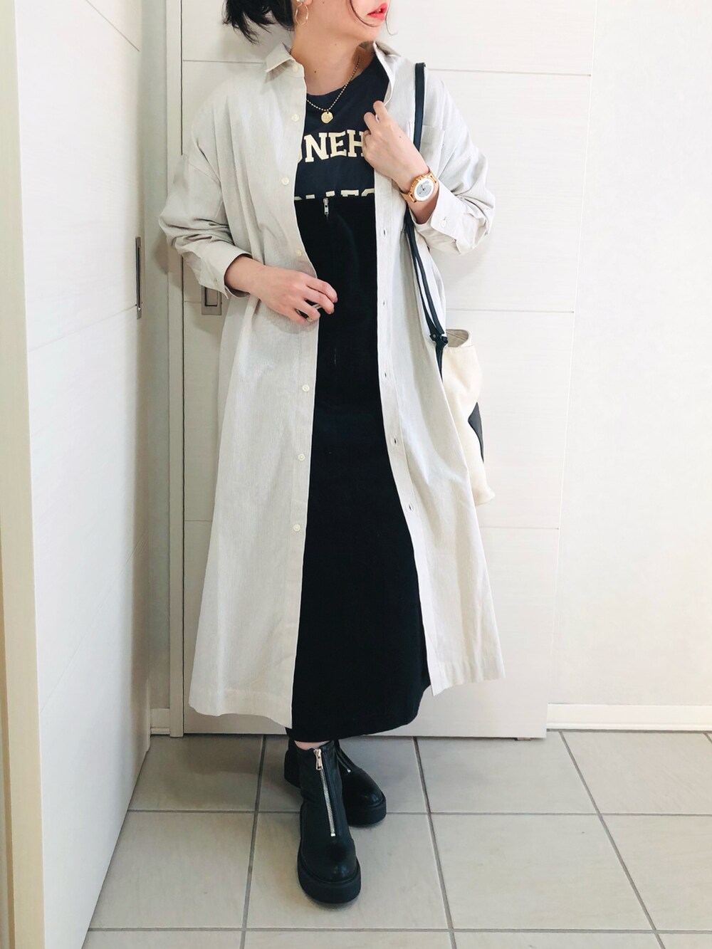 ベージュ系のワンピース、ブルー系のTシャツ/カットソー、ブラック系のジャンパースカートを着用したレディースの冬コーディネートの2枚目の写真