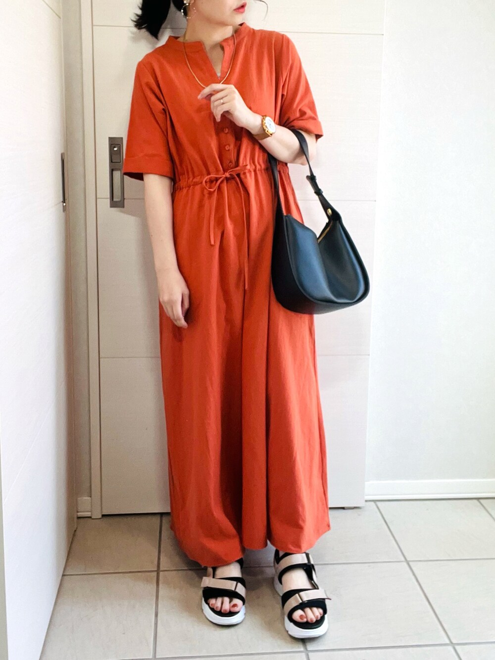 オレンジ系のワンピース、ベージュ系のサンダル、ブラック系のショルダーバッグを着用したレディースの夏コーディネートの3枚目の写真