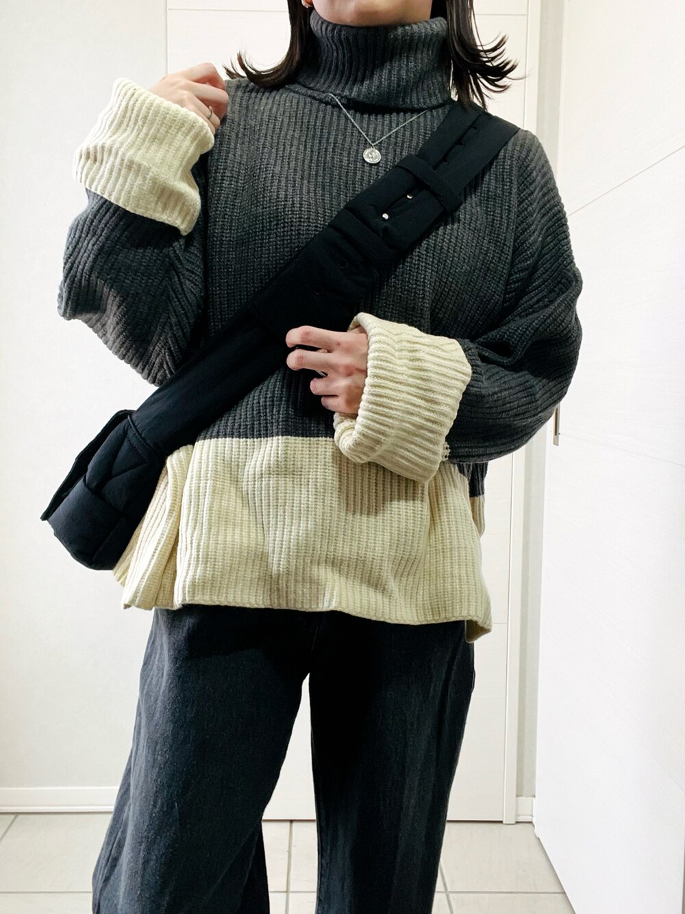 グレー系のニット/セーター、ブラック系のデニムパンツ、ブラック系のスニーカーを着用したレディースの冬コーディネートの3枚目の写真