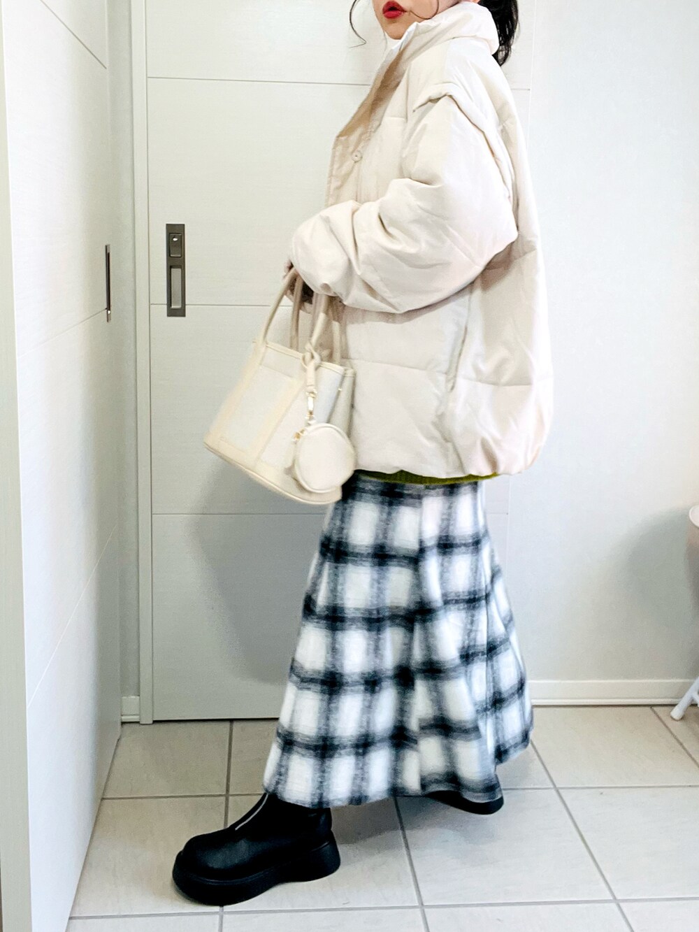 ホワイト系のダウンジャケット/コート、グリーン系のニット/セーター、ホワイト系のスカートを着用したレディースの冬コーディネートの5枚目の写真